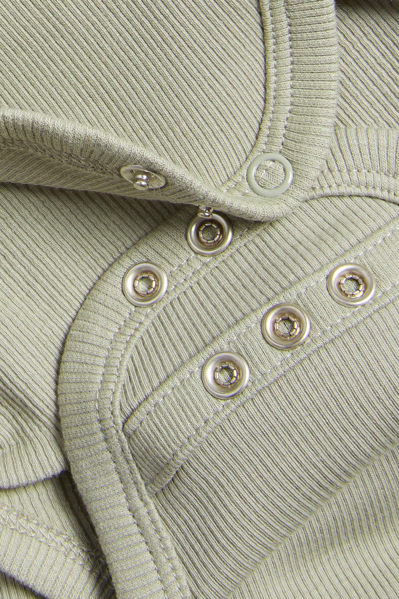 Zbliżenie na ciemnozielone prążkowane body niemowlęce z zapięciem na zatrzaski.