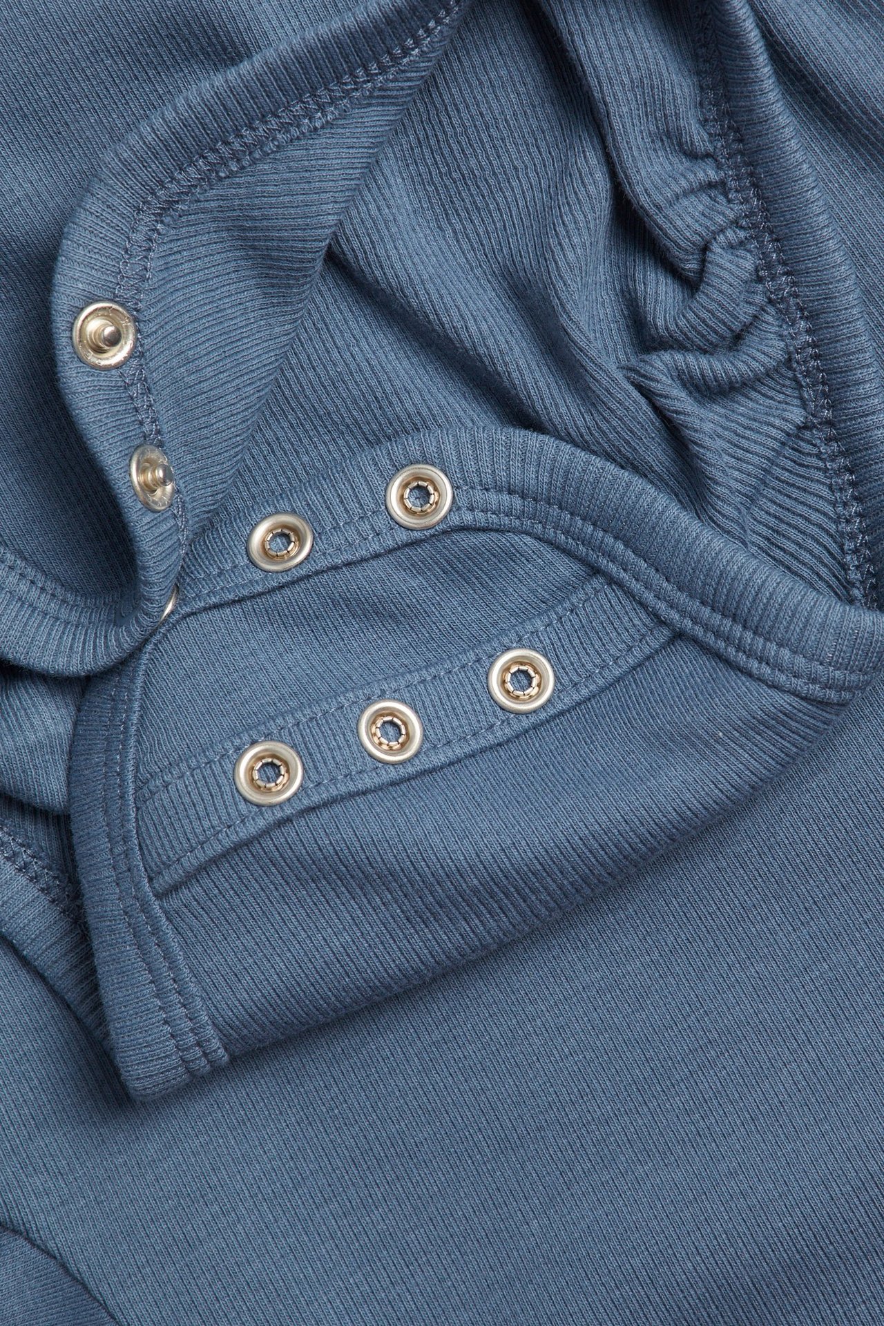 Zbliżenie niebieskiego prążkowanego body niemowlęcego z podwójnymi rzędami zatrzasków.