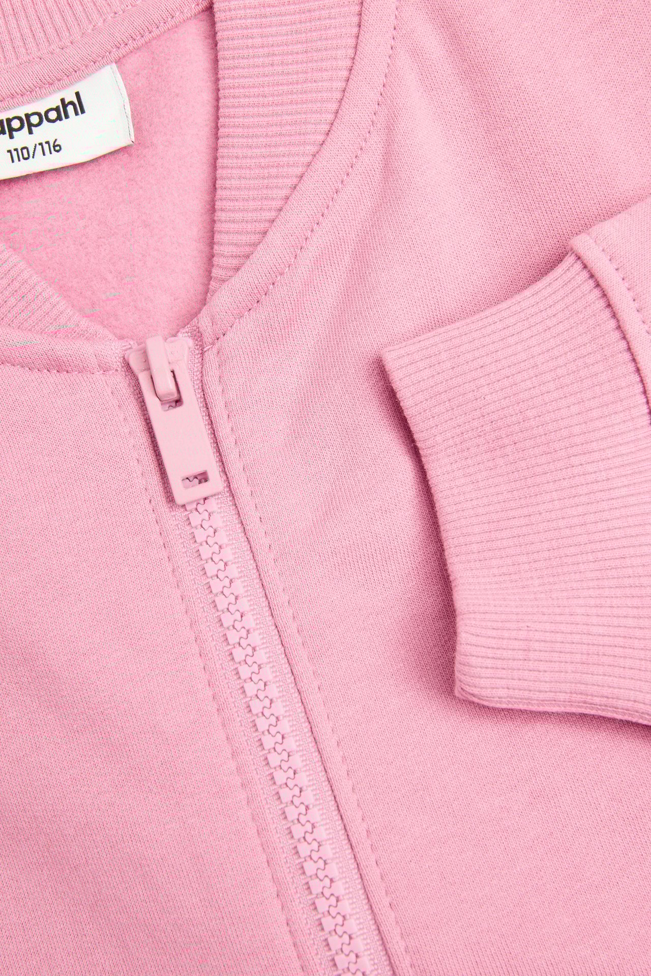 Zbliżenie różowego bawełnianego swetra dziecięcego z zamkiem błyskawicznym z przodu oraz prążkowanym kołnierzem i mankietem.