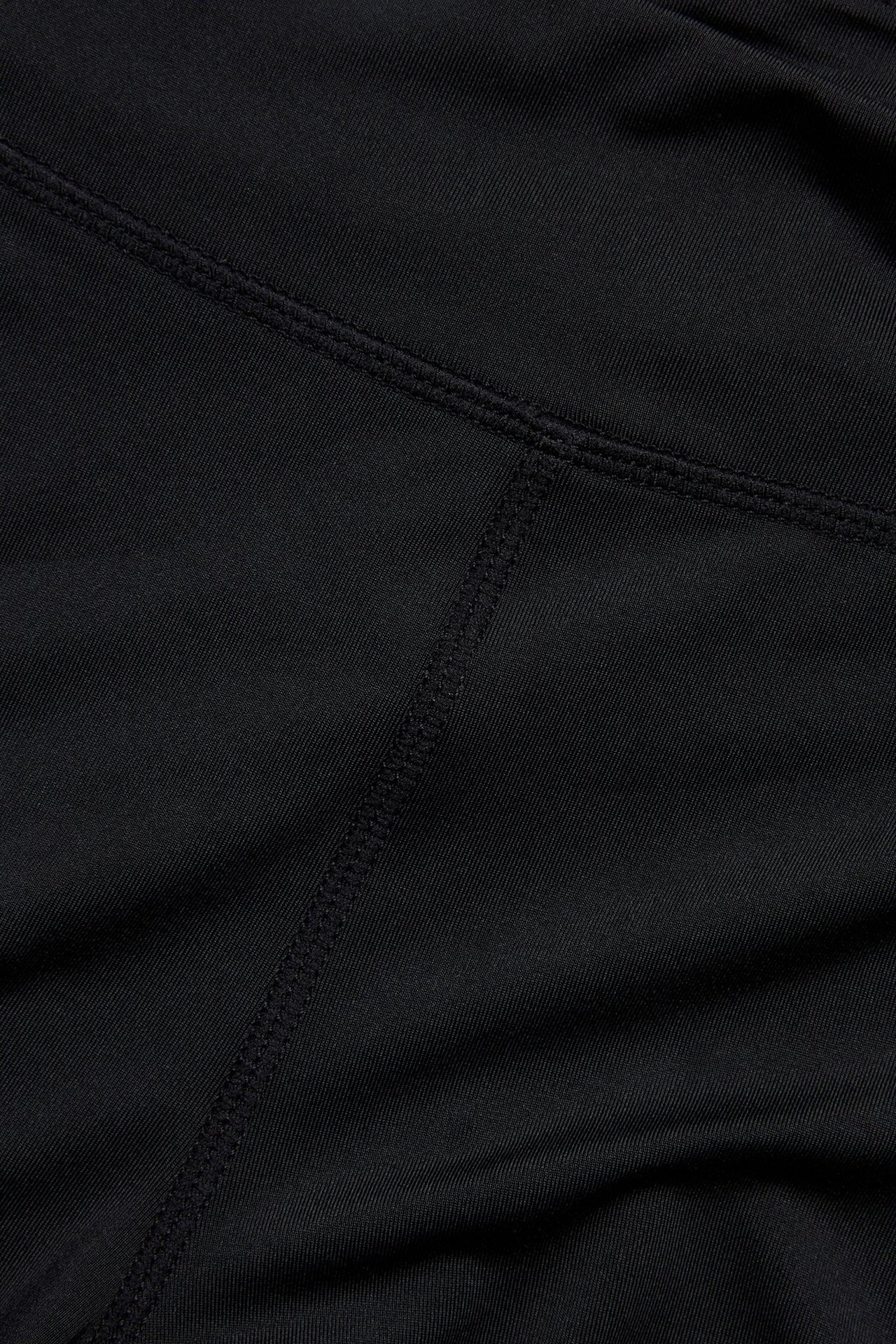 Zbliżenie czarnego, jednolitego materiału spodenek rowerowych z widocznymi szwami.