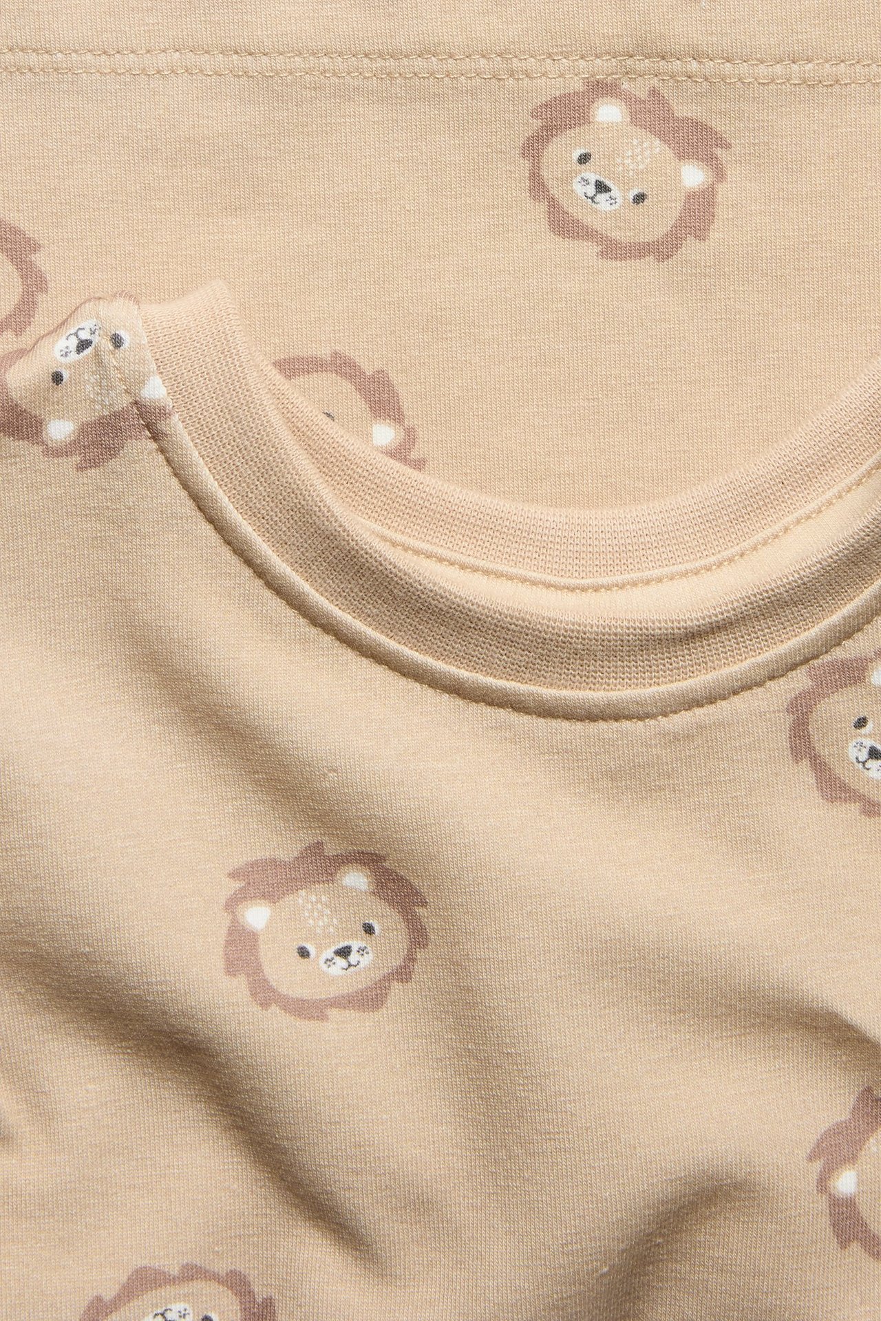 Zbliżenie beżowego bawełnianego t-shirtu niemowlęcego z wzorem lwa.
