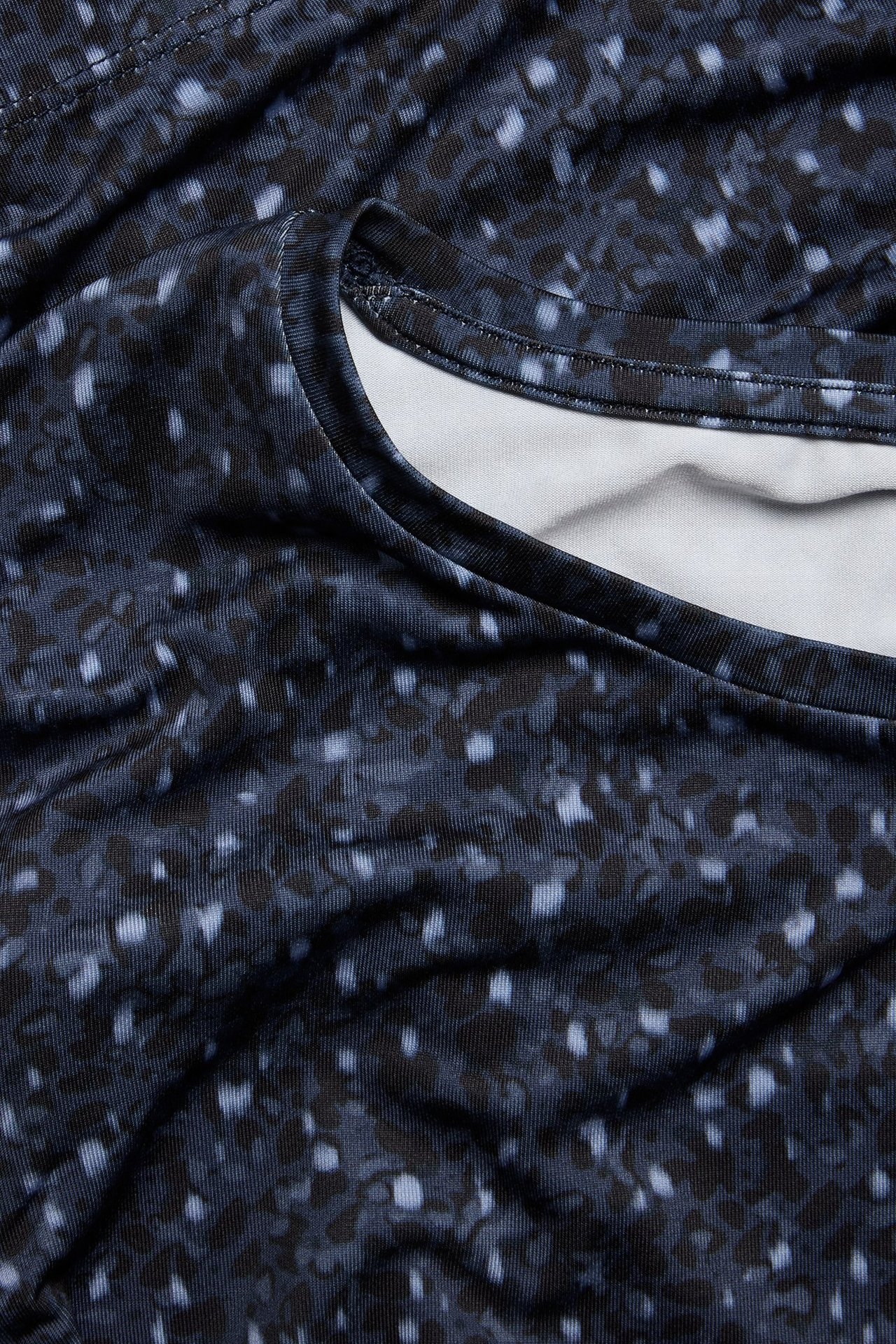 Zbliżenie na niebieski wzorzysty, dopasowany top treningowy z okrągłym dekoltem.