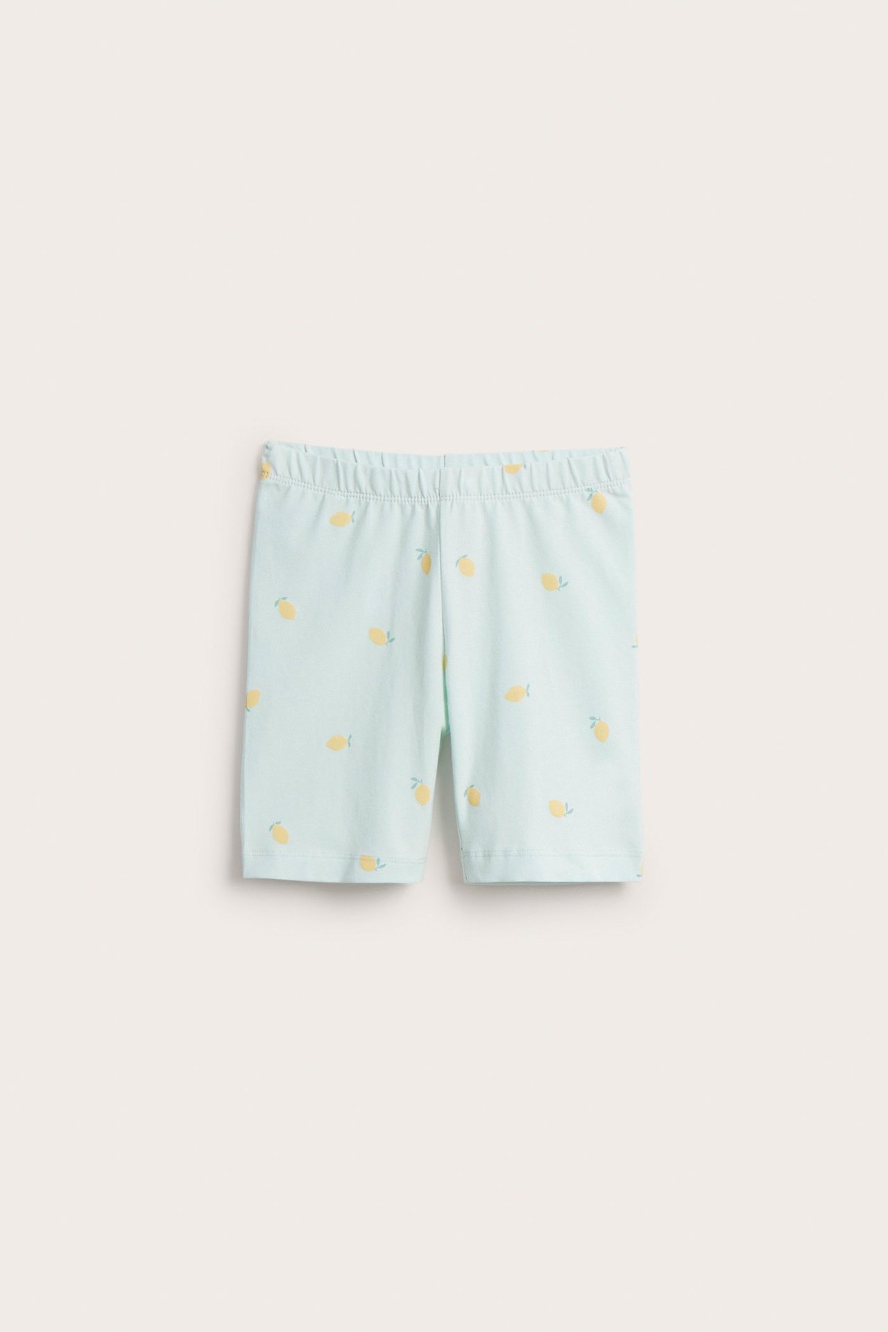 Widok z przodu: Jasnozielone bawełniane szorty rowerowe dla dzieci, z żółtym wzorem w cytryny i elastycznym pasem.