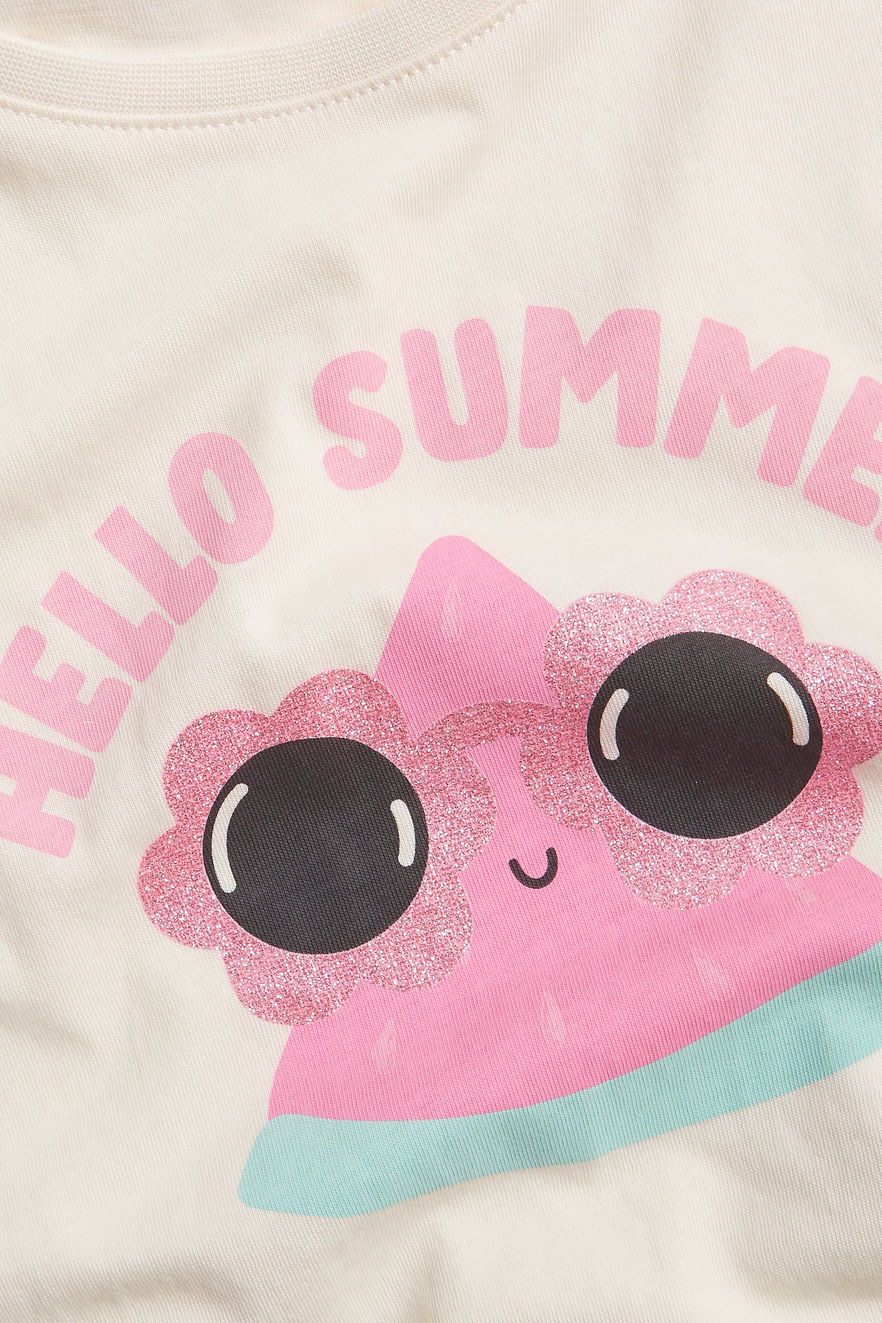 Närbild av en offwhite bomulls t-shirt för barn med rosa "Hello Summer" och vattenmelon tryck.