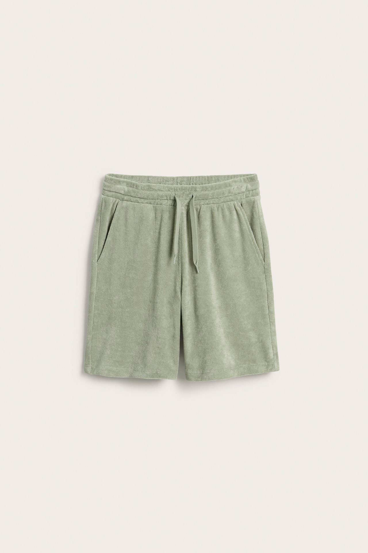 Frontvy av mörkgröna frottéshorts med resår i midjan, dragsko och två framfickor.
