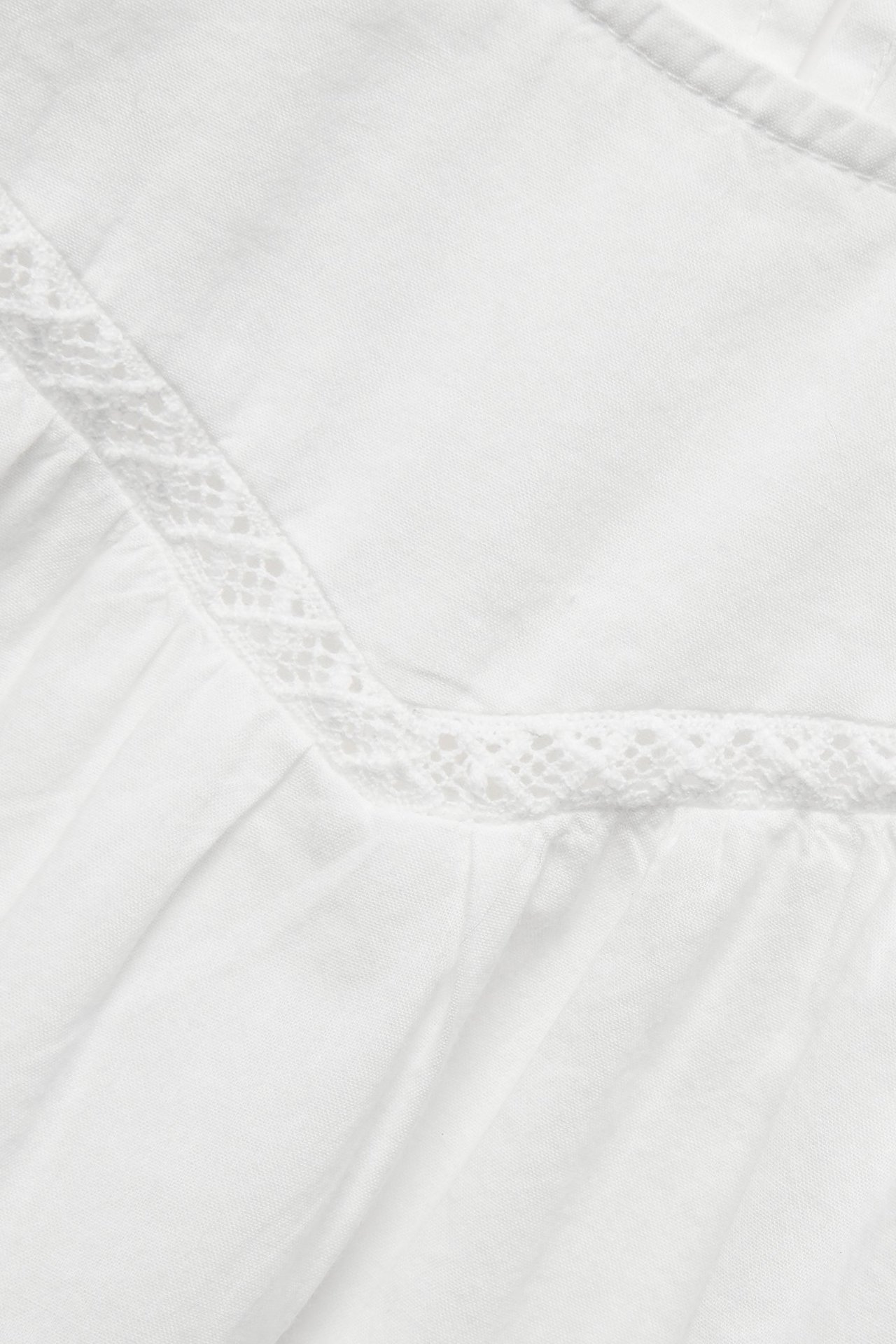 Zbliżenie na ecru bawełnianą bluzkę z delikatną koronkową lamówką i miękkimi falbankami.