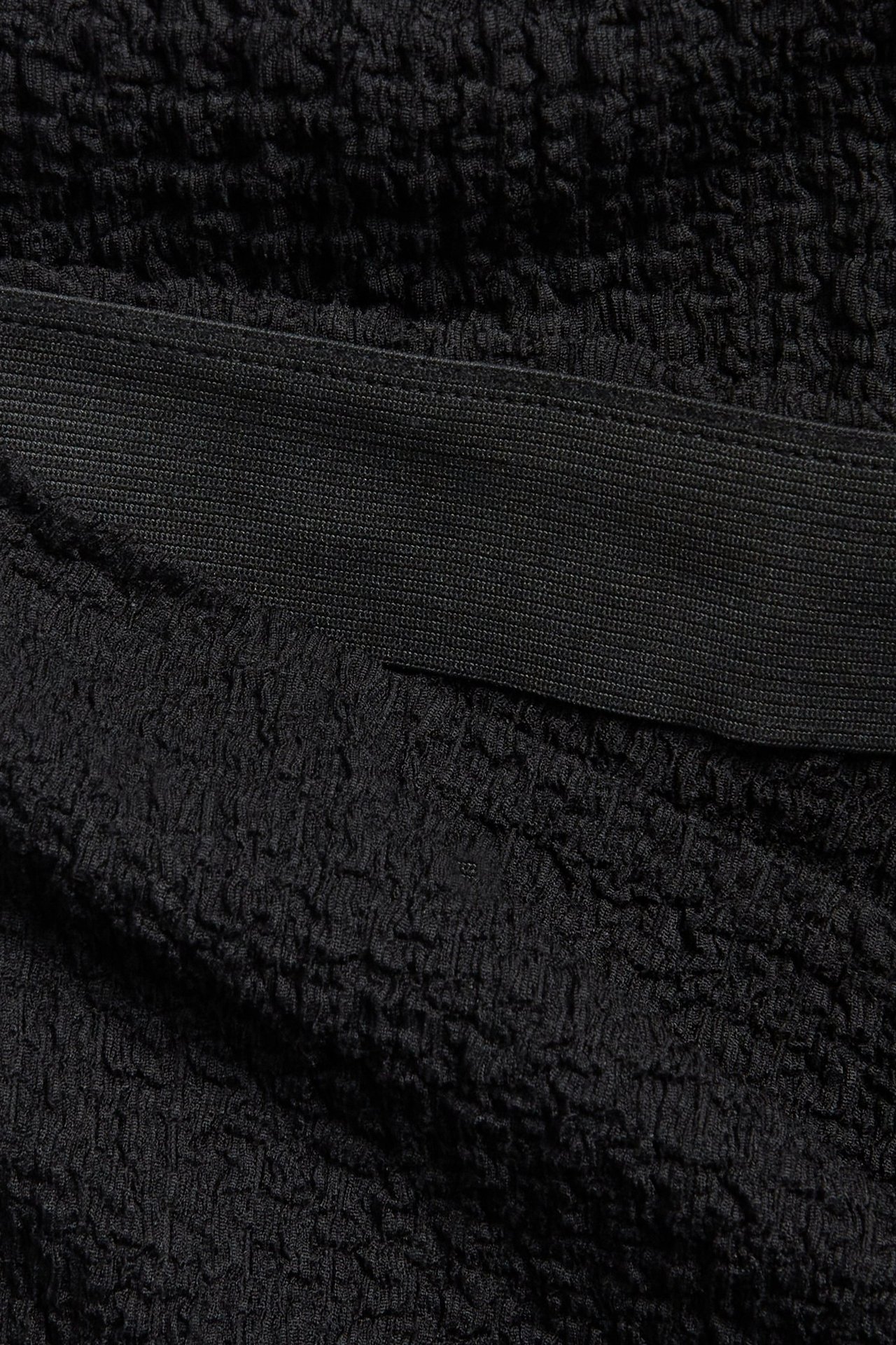 Zbliżenie na czarne, bąbelkowe spodnie typu pull-on z dżerseju z elastyczną talią.