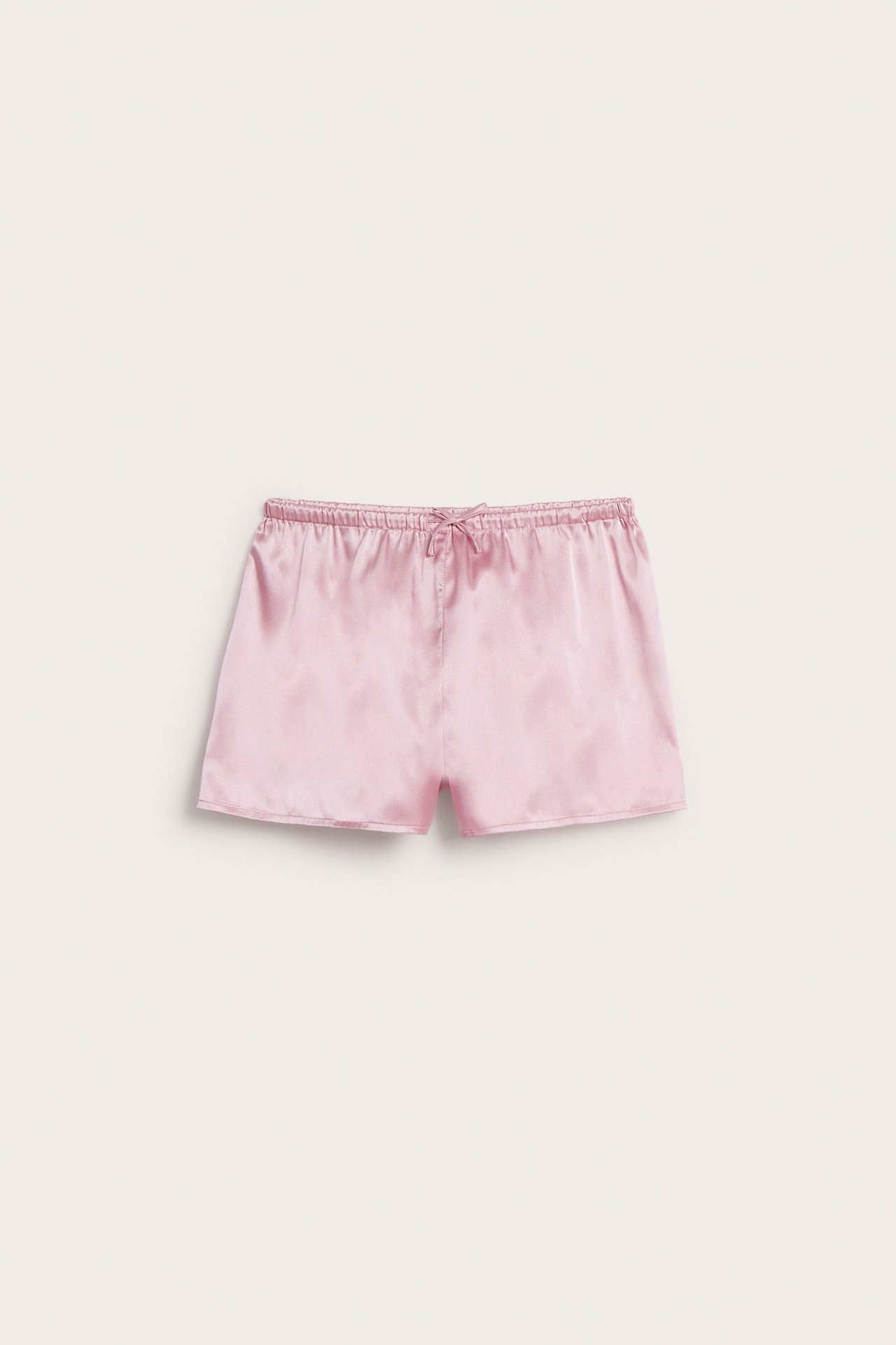 Frontvy av ljusrosa pyjamasshorts i satin med resår och dragsko i midjan.