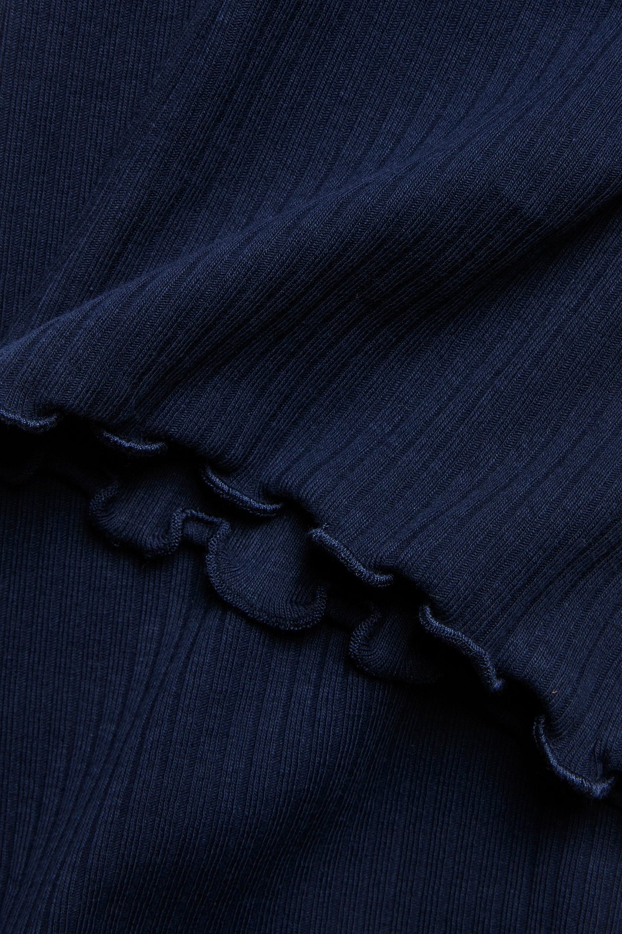 Zbliżenie na granatowe prążkowane legginsy flare z obszyciem babylock.