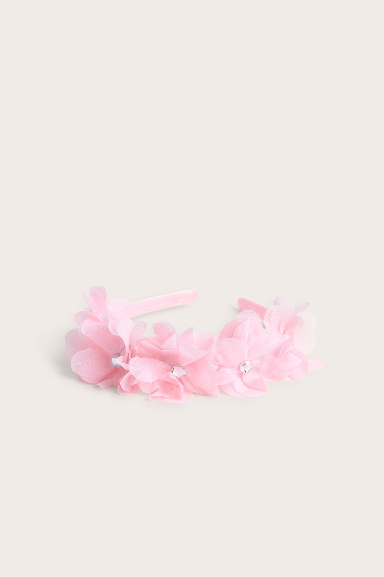 Forfra, rosa blomsterdiadem med gjennomsiktige polyesterblomster og små klare strassdetaljer.