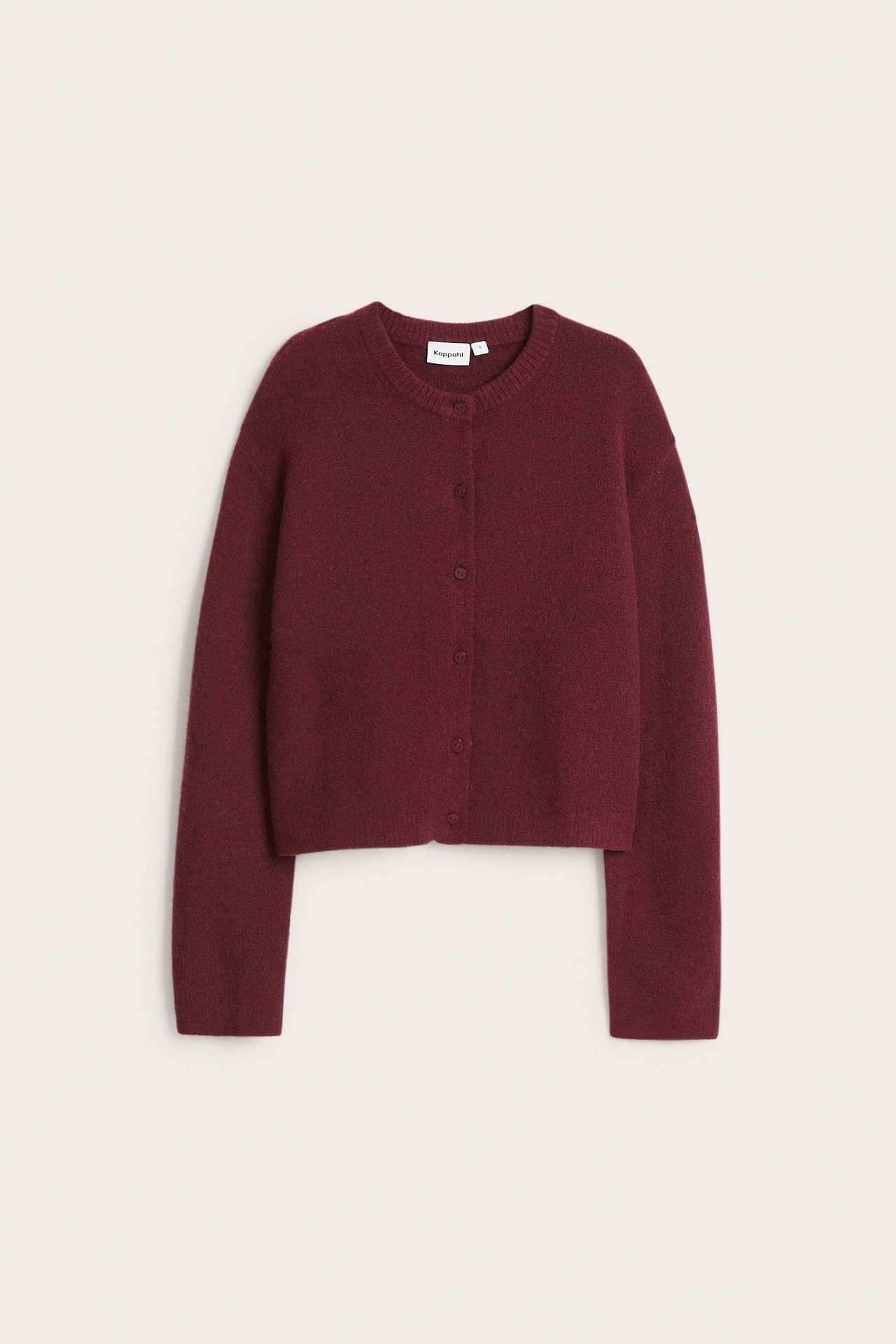 Edestä näkymä tummanpunaisesta hienoneulotusta lyhyestä neuletakista, jossa pyöreä kaula-aukko ja napit.