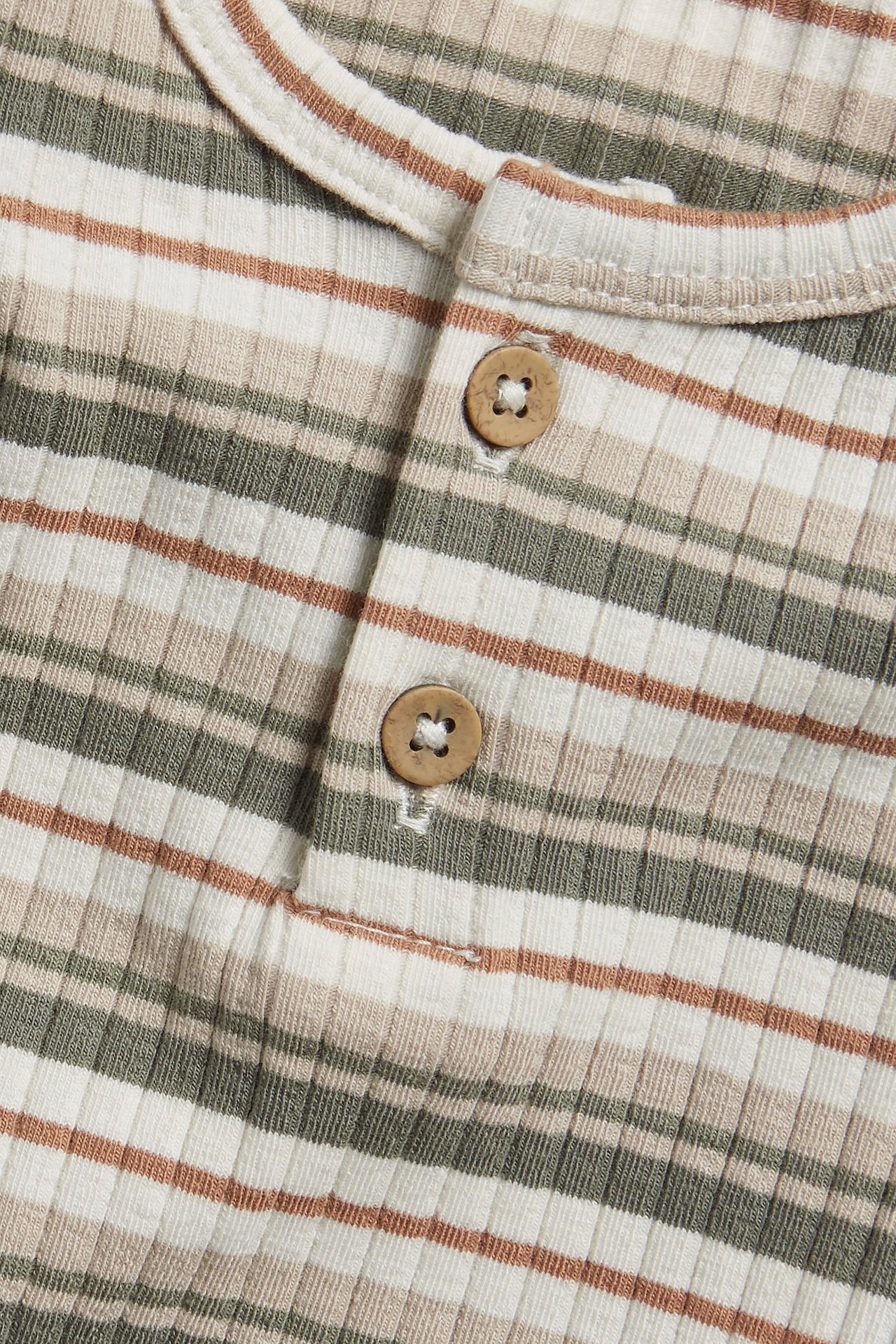 Zbliżenie: Prążkowane body z długim rękawem, złamana biel, brązowo-zielone paski, drewniane guziki.