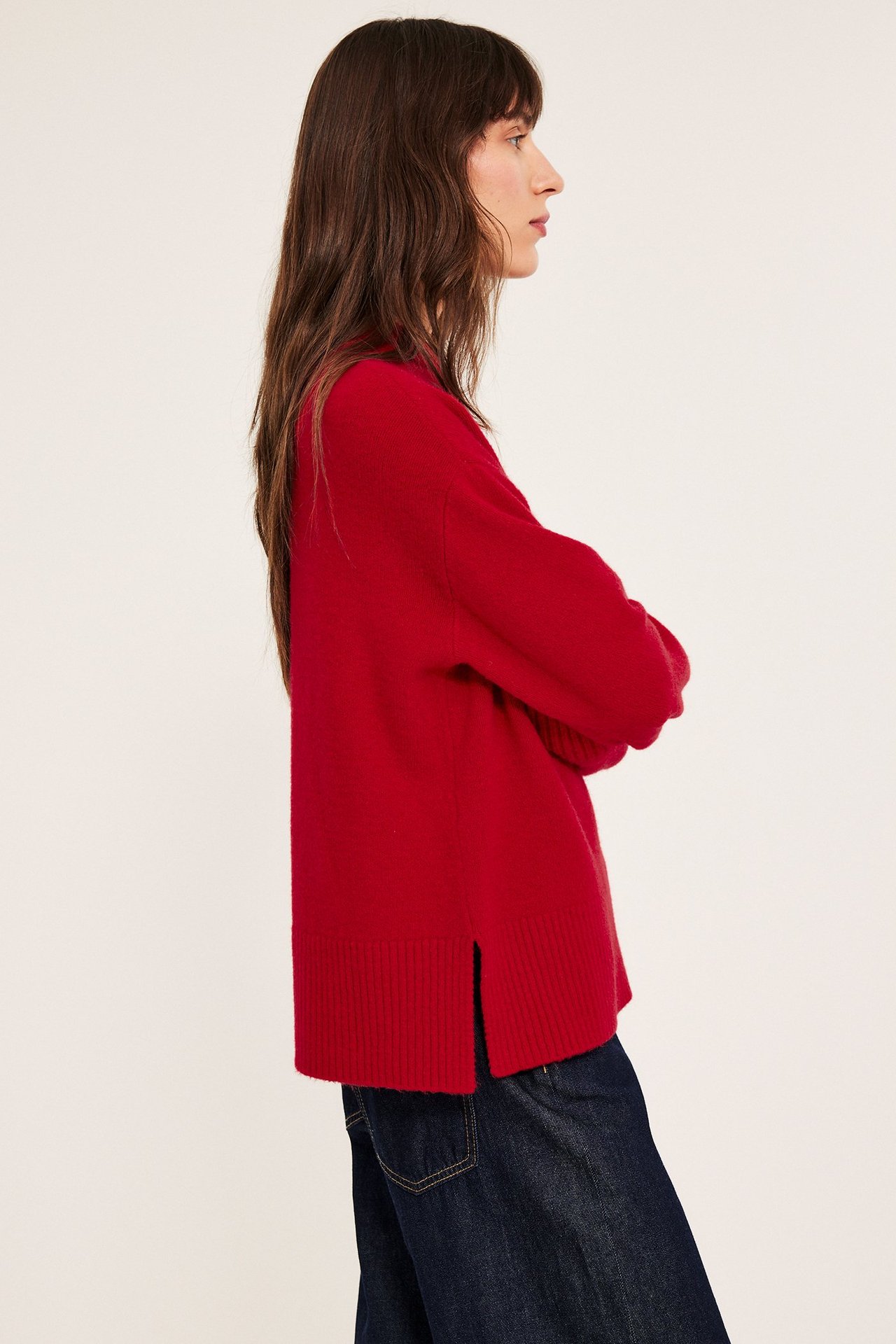 Voksen kvinne i rød strikket genser med rund hals, sideutsnitt, med ribbet kant.