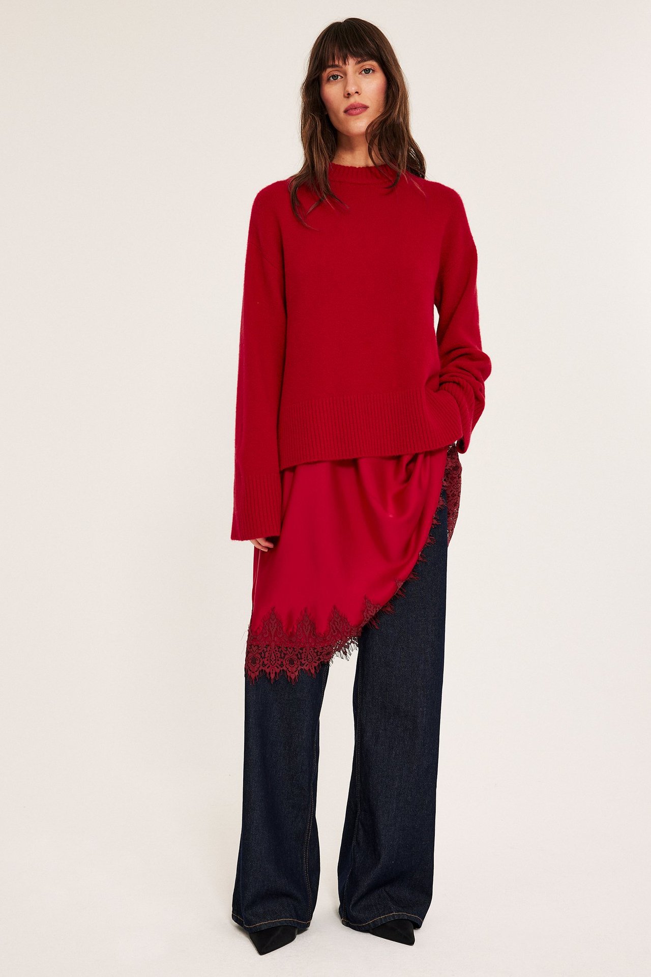 Kvinne iført rød genser med rund hals og rød satinlignende nederdel med blondekant.