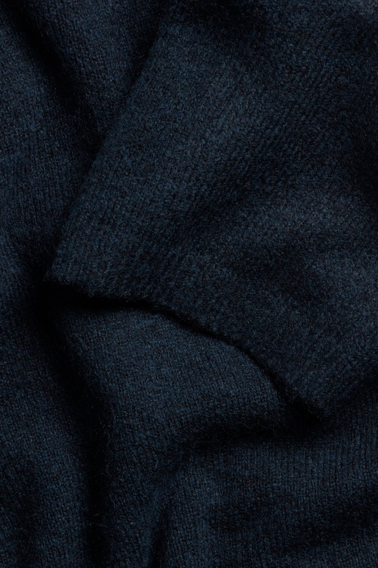 Lähikuva tummansinisestä yksivärisestä neulekankaasta oversized t-paidassa, näyttäen rakennetta.