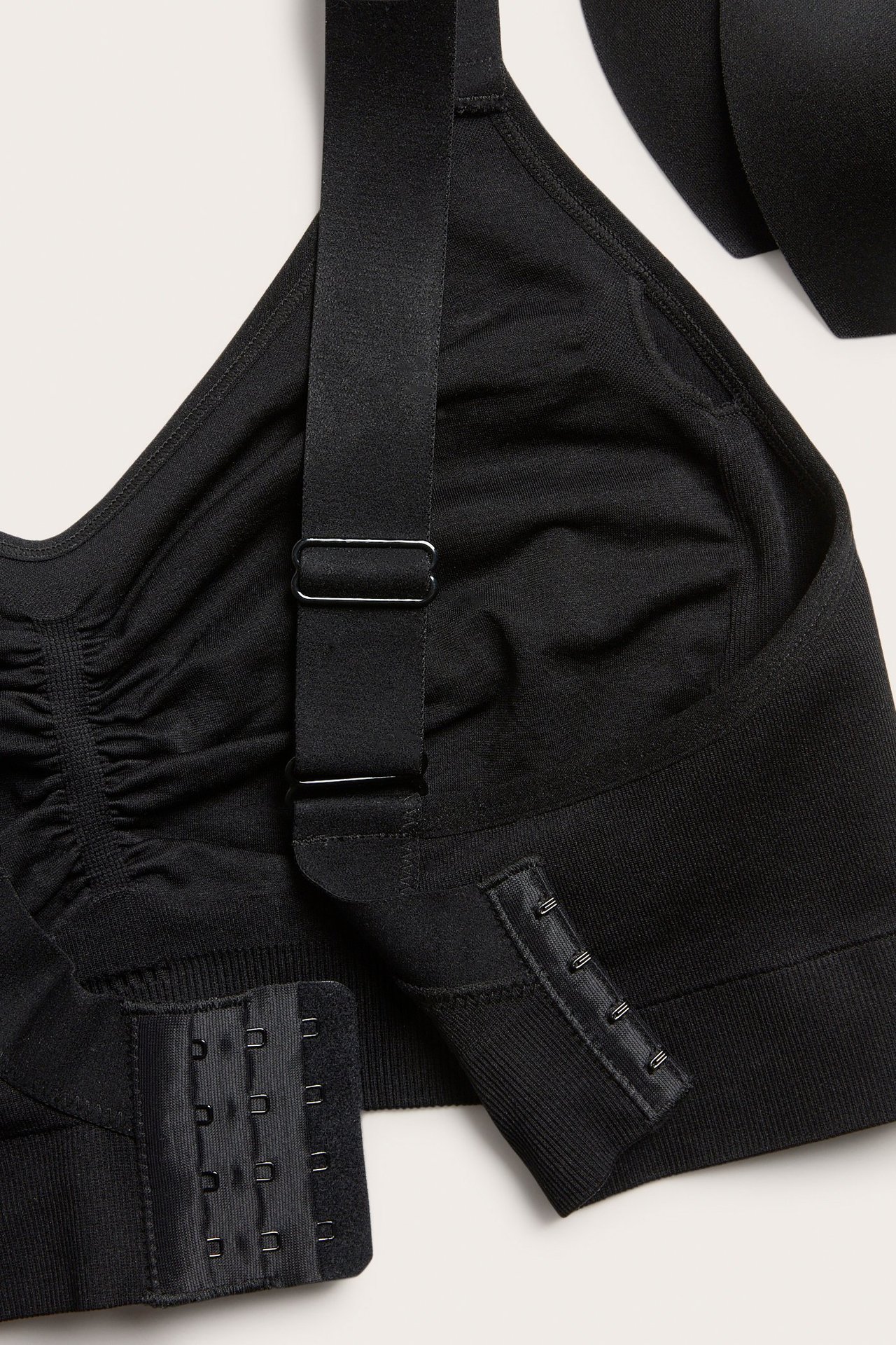 Zbliżenie czarnego bezszwowego biustonosza bez fiszbin z regulowanymi ramiączkami i wyjmowanymi wkładkami.