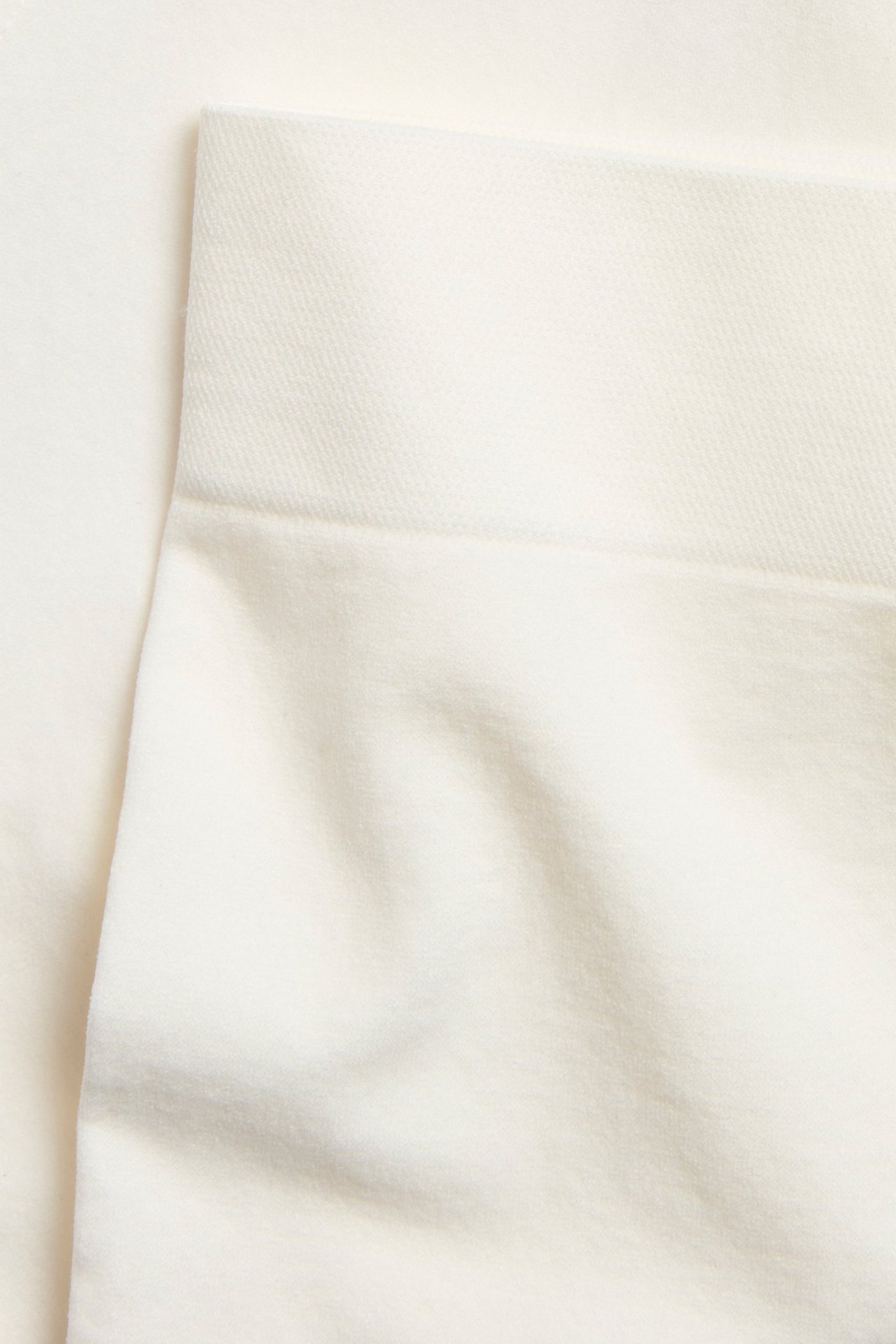 Zbliżenie białych bezszwowych bokserek, ukazujące gładki materiał i szeroki pas.