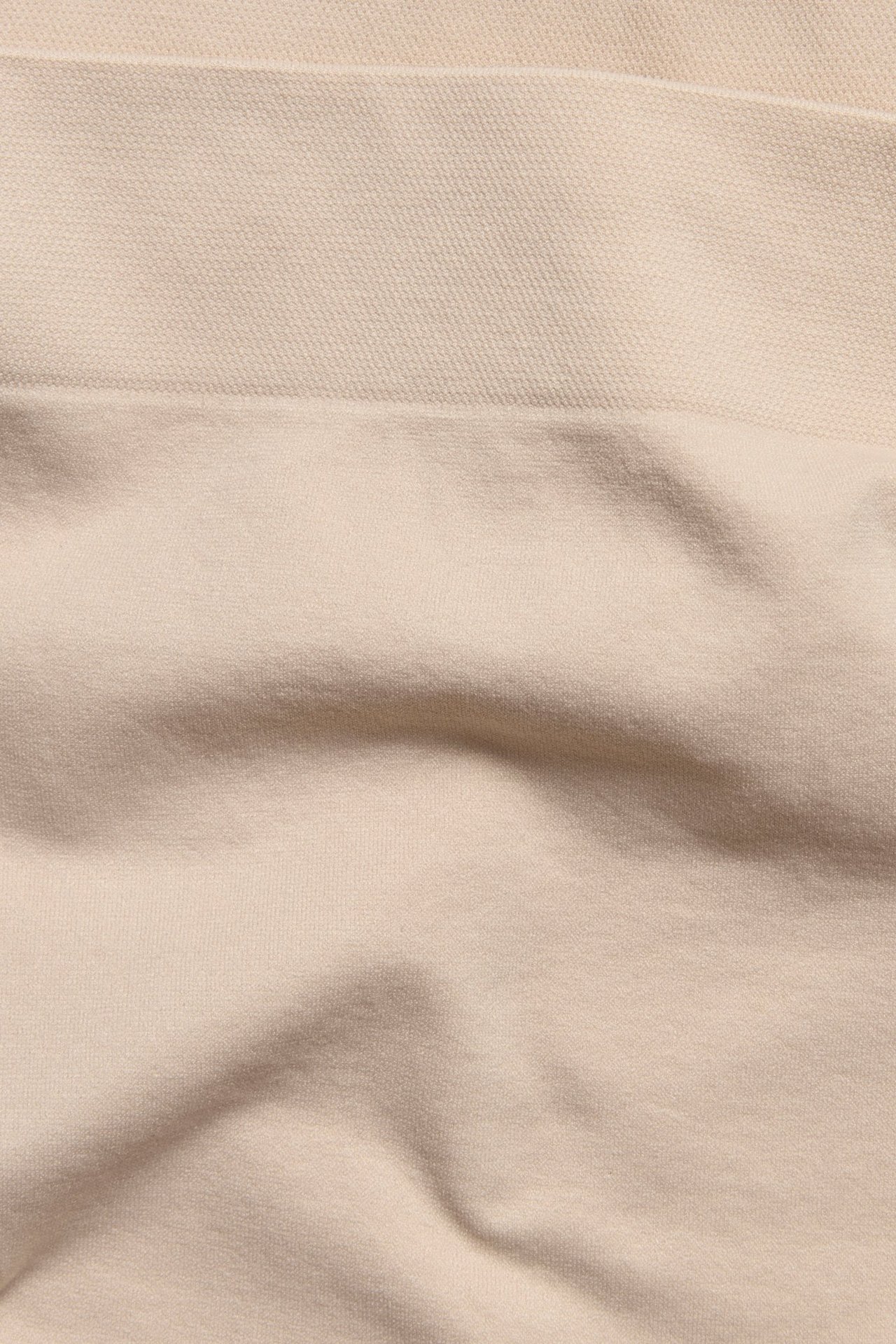 Zbliżenie na jasnoróżowy, bezszwowy materiał bokserek, ukazujące gładką, miękką teksturę z delikatnymi fałdami.