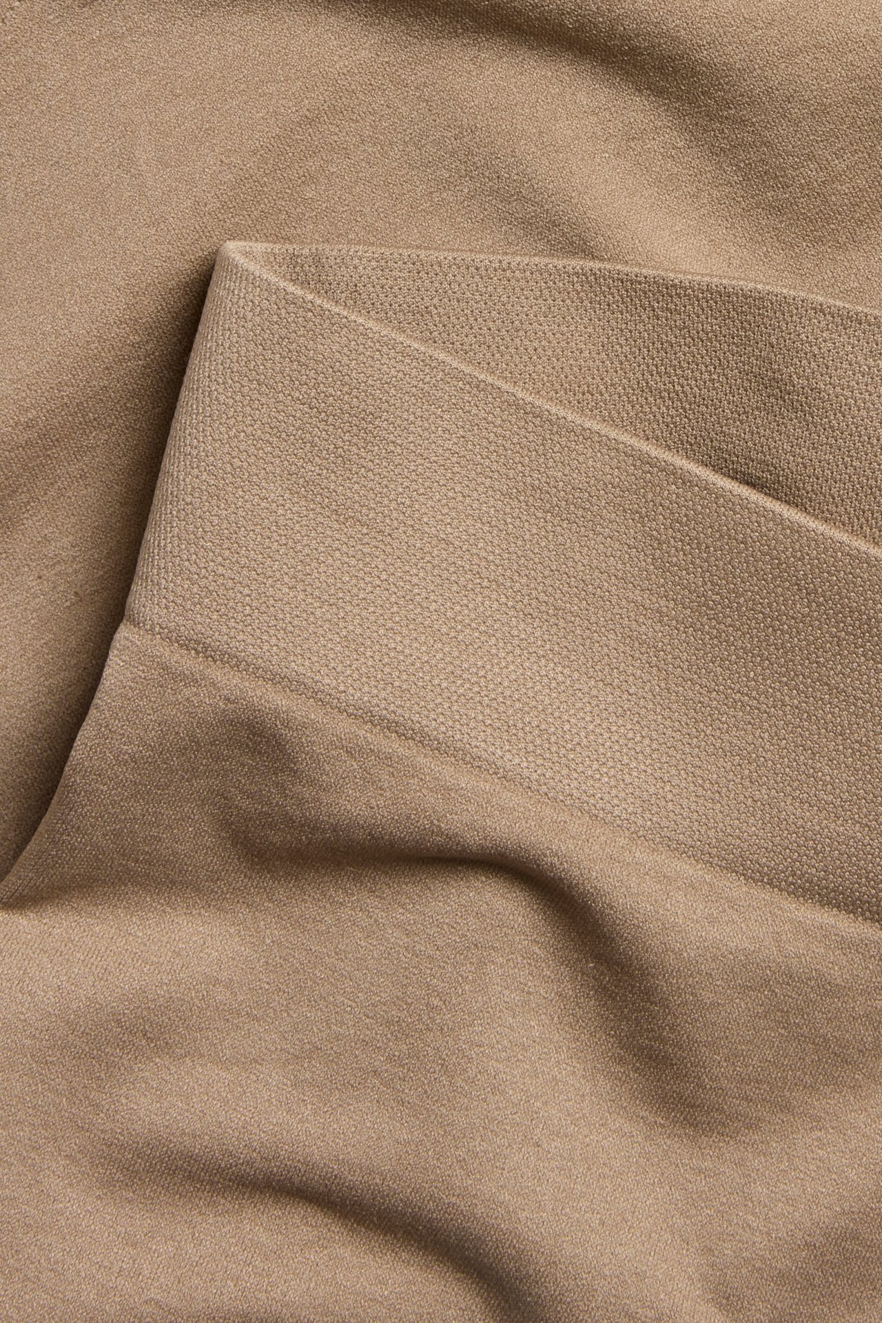 Zbliżenie beżowego, bezszwowego materiału bokserek, ukazujące jego gładką teksturę i elastyczny pas.