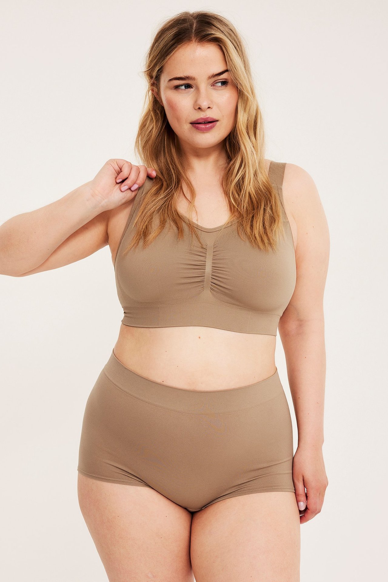 Forfra, kvinne i beige sømløse boxershorts og matchende sømløs BH med rynkede detaljer.