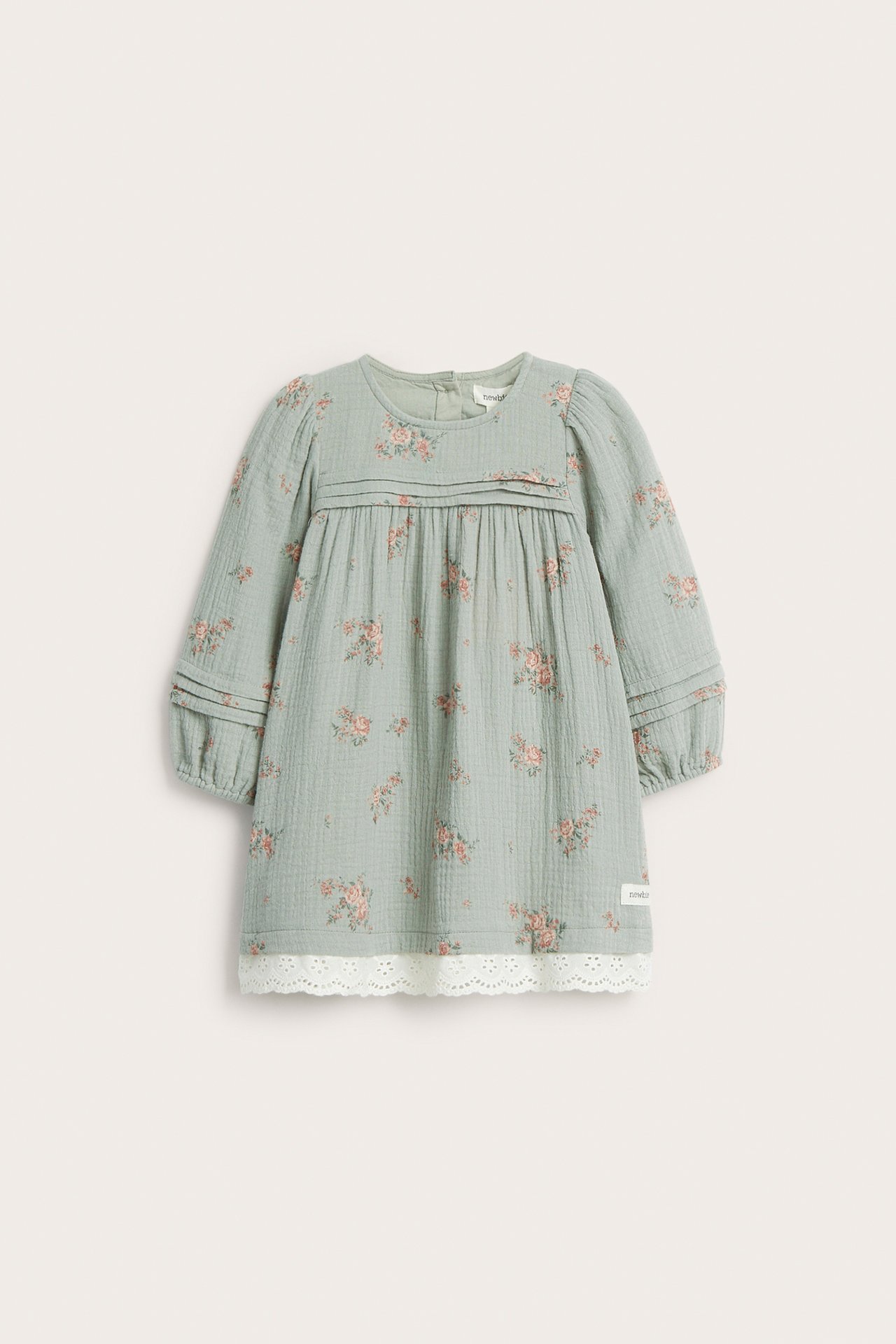 Widok z przodu: Zielona bawełniana sukienka dziecięca w różowe kwiaty, z zakładkami i białą koronką.