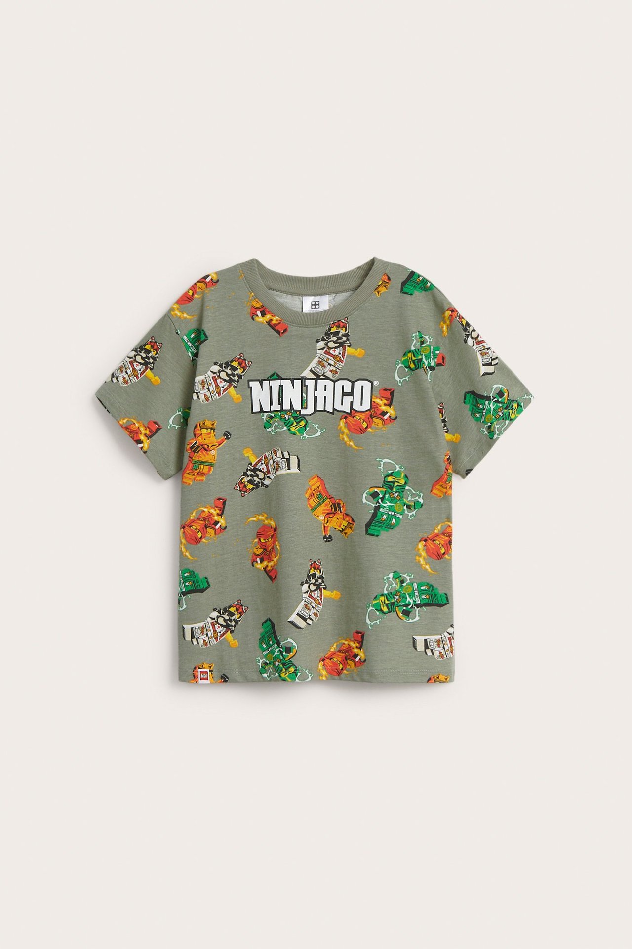 Frontvy av en mörkgrön oversized T-shirt i bomull för barn med Ninjago-tryck och text framtill.