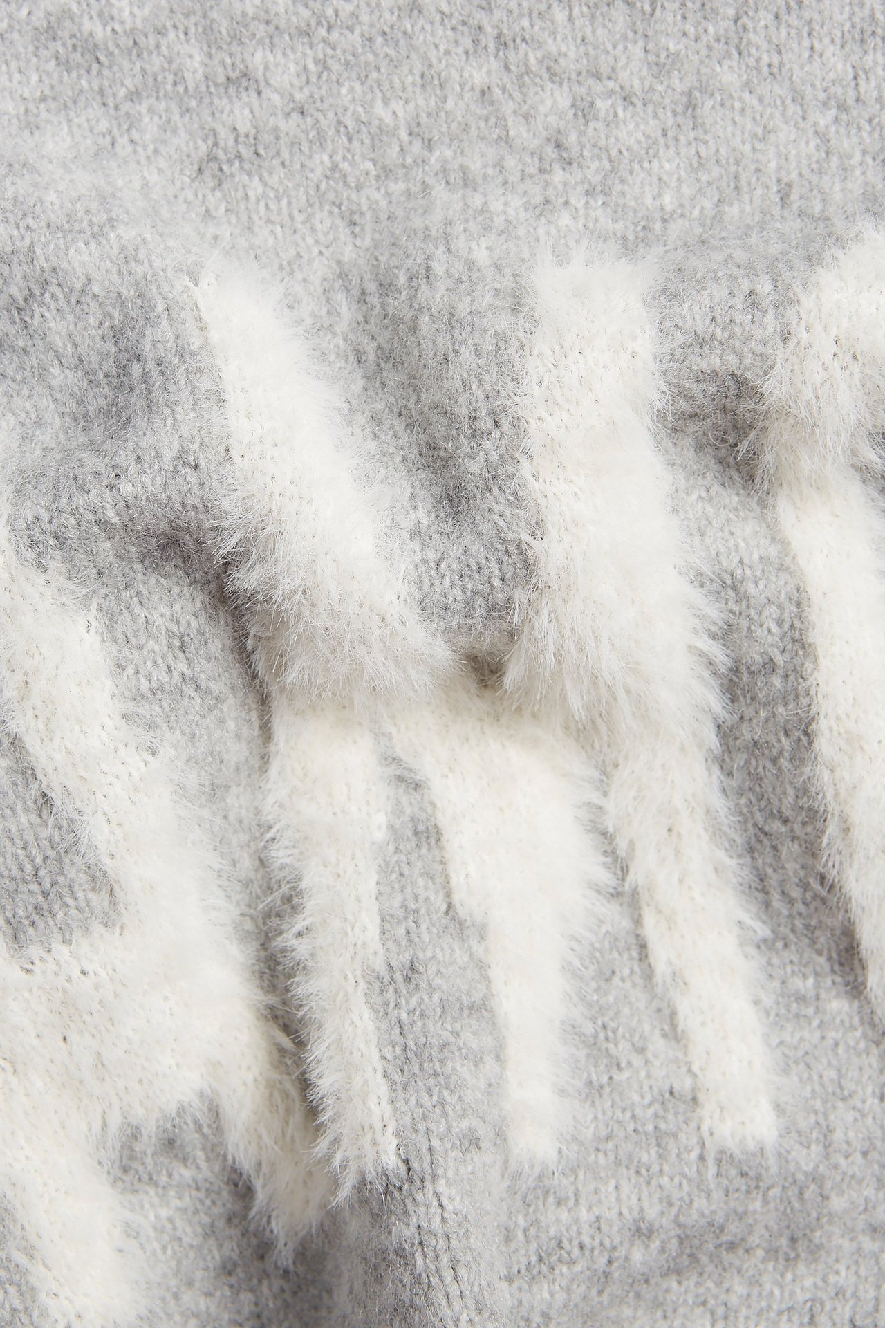 Zbliżenie na szary melanżowy sweter z białym, puszystym wzorem żakardowym z tekstem.