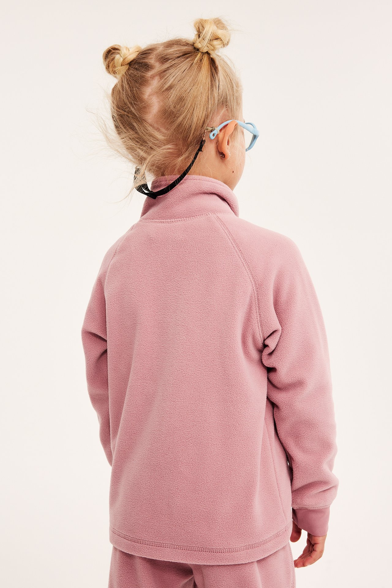 Barn tjej med rosa fleecejacka med zip-in / zip-off funktion, sett från bak.
