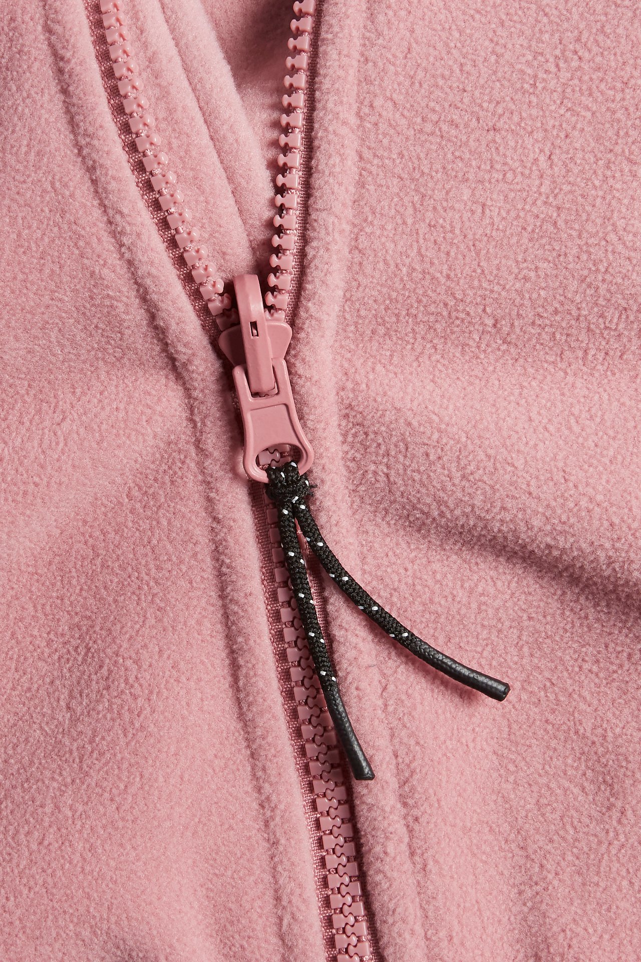 Närbild av en rosa fleecejacka med rosa dragkedja och svart dragkedjerep.