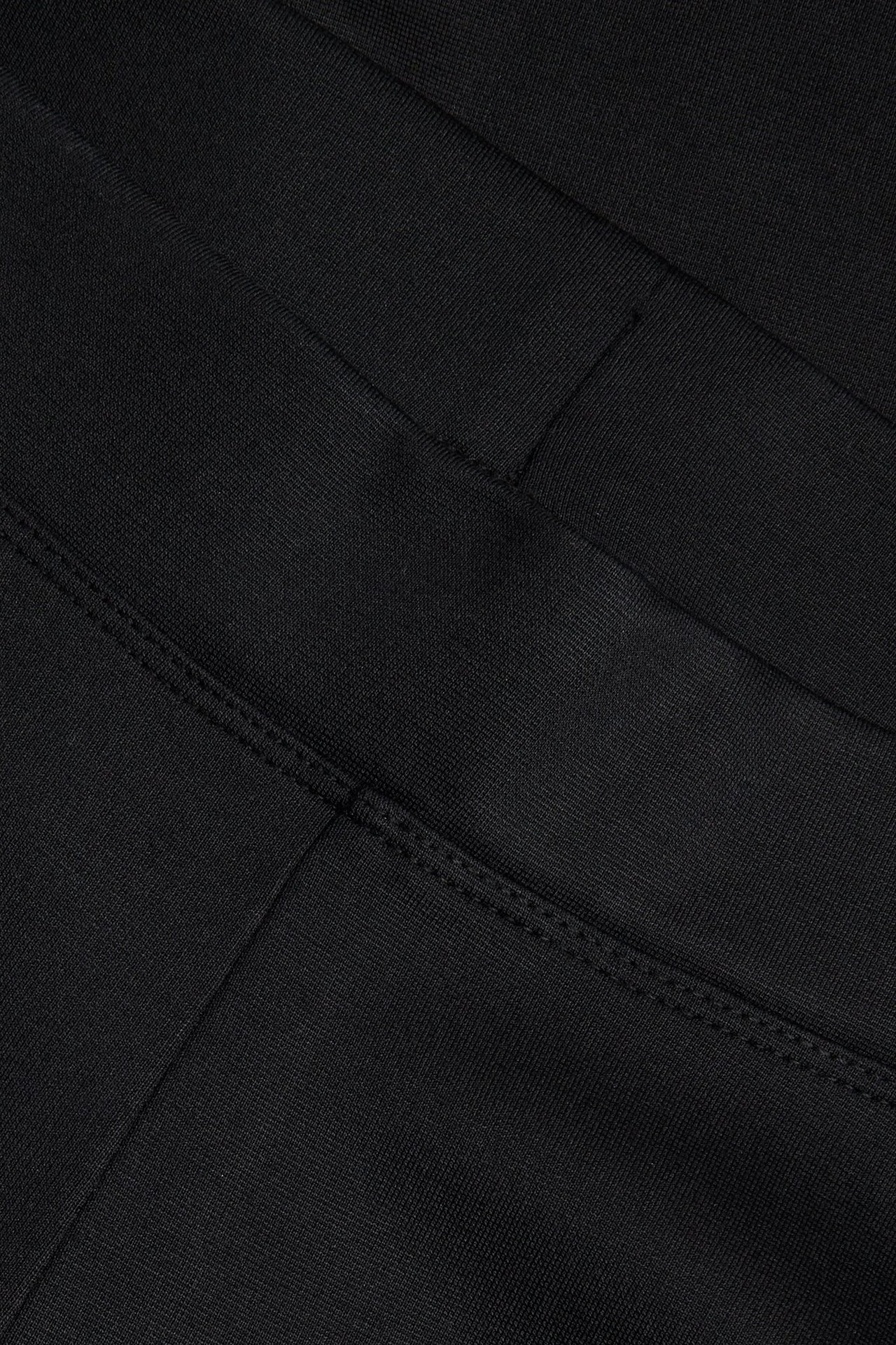 Närbild av svarta bootcut-byxor i jerseykvalitet med synliga sömmar.