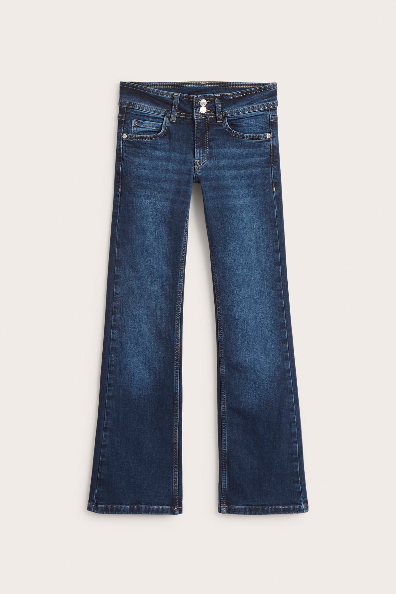 Widok z przodu ciemnych dżinsów bootcut dla dzieci z niskim stanem i podwójnym zapięciem na guziki.
