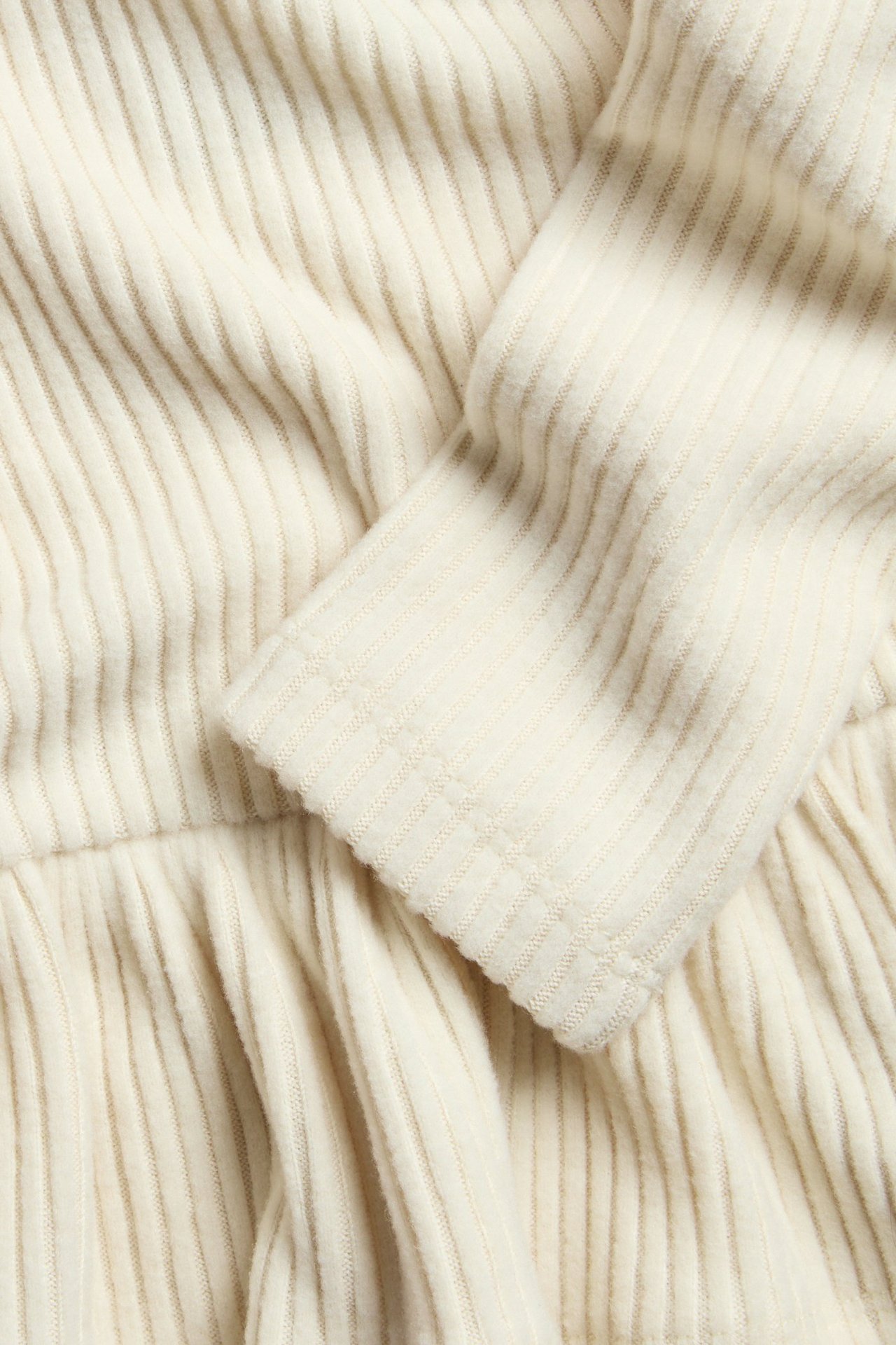 Vaaleanbeige pitkähiainen peplum toppi pehmeää ribbipolyesteri-viskoosisekoitetta.