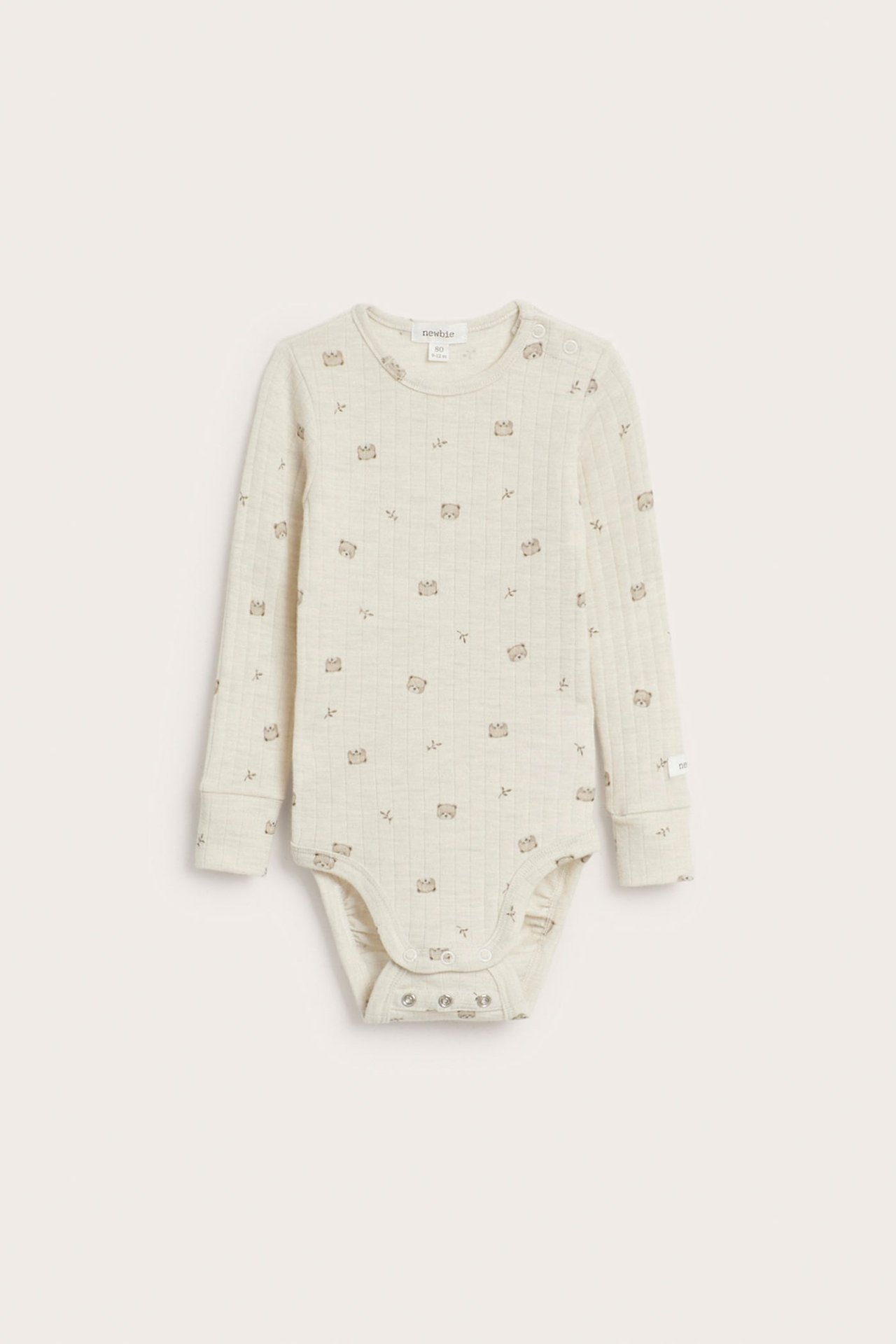 Frontbilde av en lys beige vattert babybody med lange ermer, bjørnemønster og trykknapper.