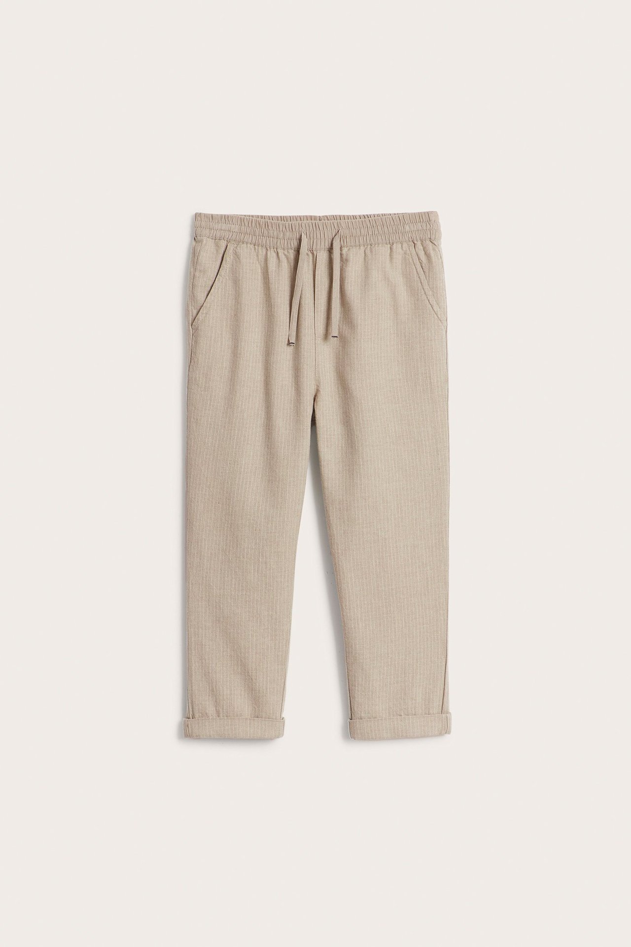 Frontvy: Barnbyxor i beige melerad randig vävd bomull med resår och dragsko i midjan samt uppvikta benslut.