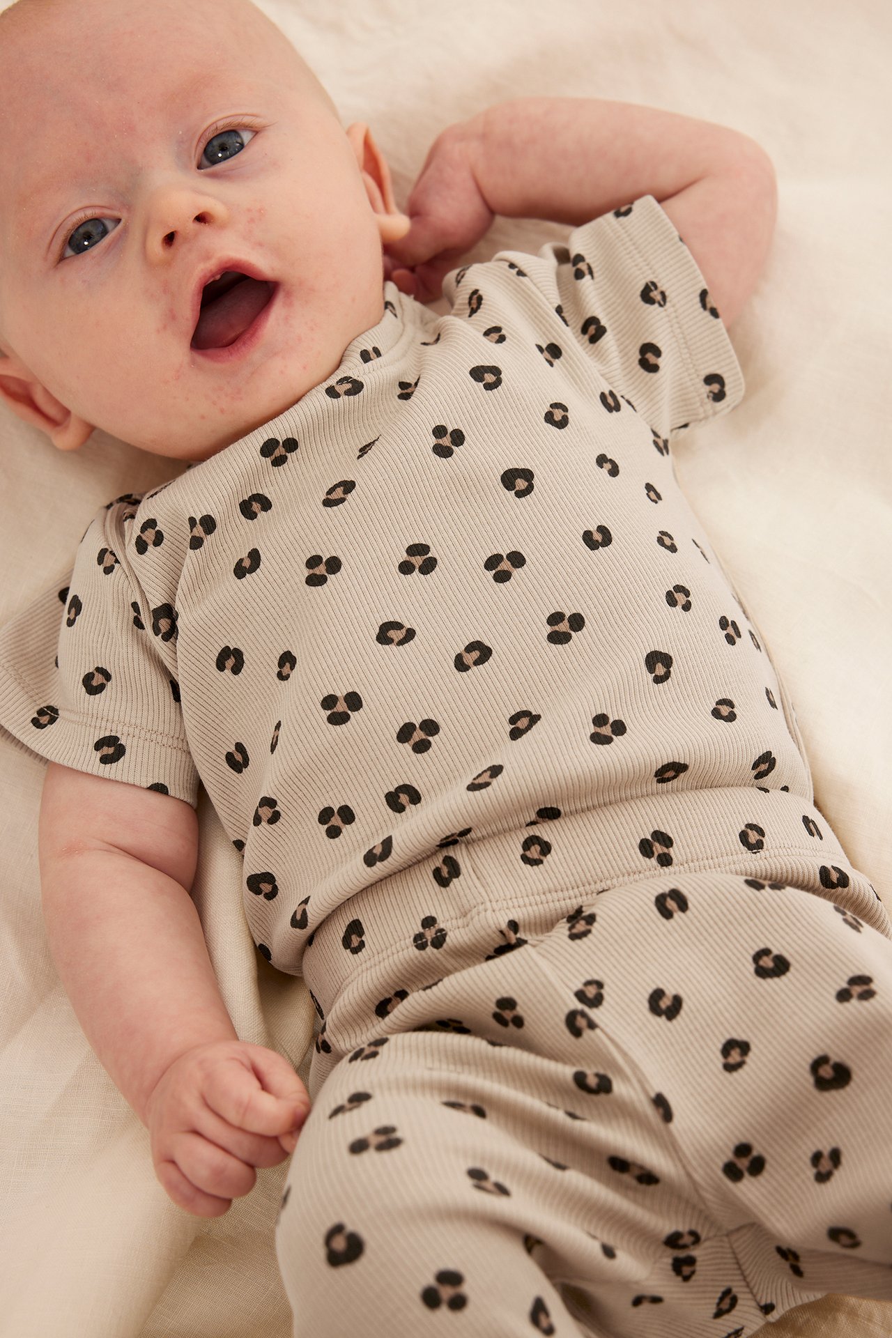 Lähikuva vauvasta yllään beige ribattu lyhythihainen body mustalla leopardikuviolla ja yhteensopivat housut.