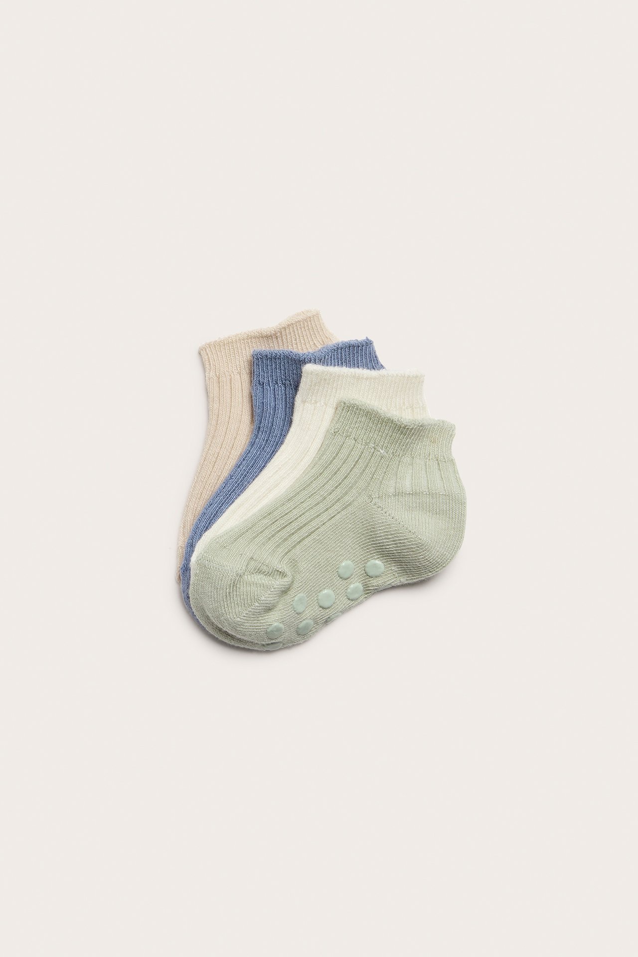 Närbild av fyra ribbade babyankelstrumpor: grön, beige, blå, benvit, med halkskydd.