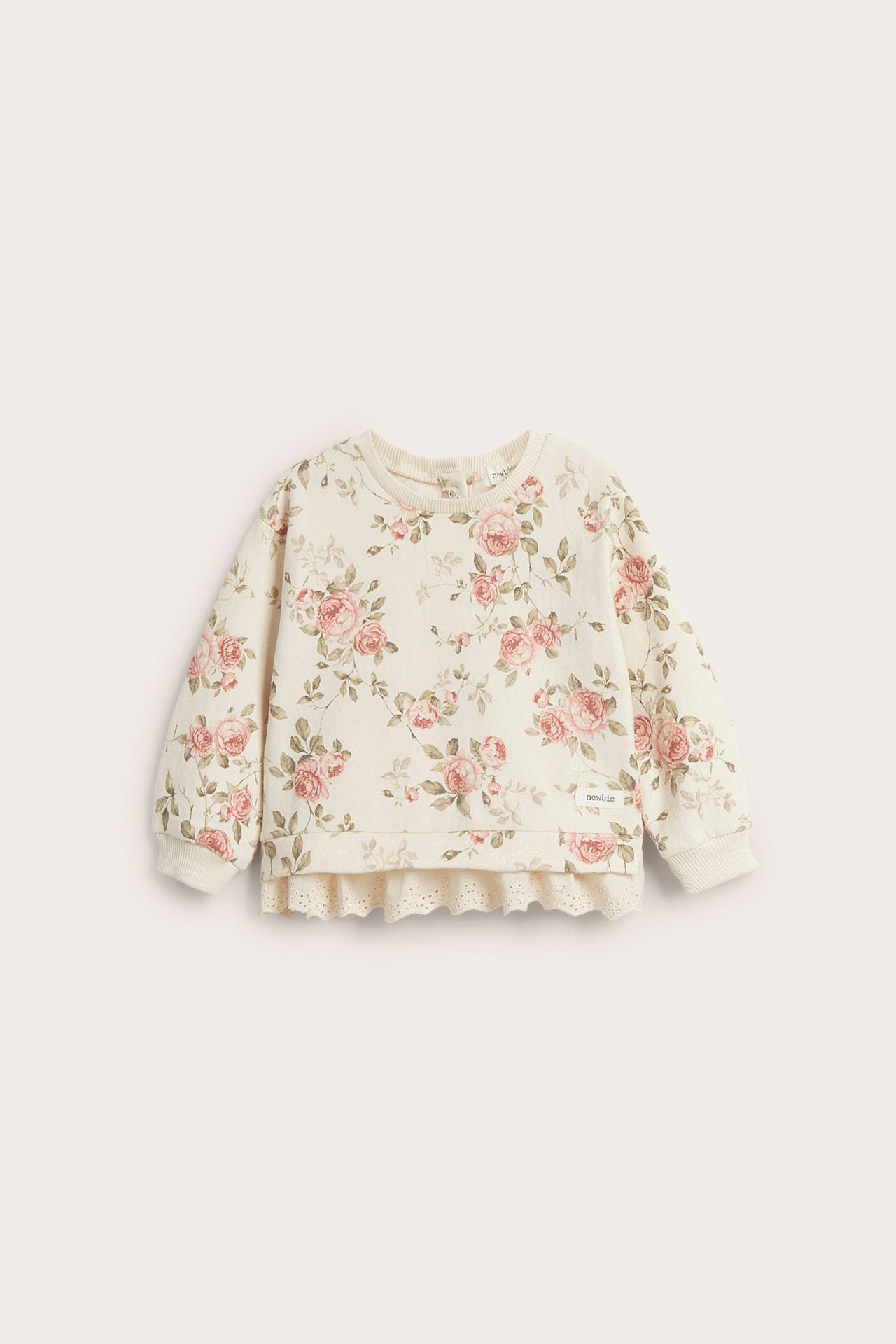 Widok z przodu: beżowa bluza niemowlęca w kwiaty, z bufiastymi rękawami, ściągaczami i koronkowym dołem.