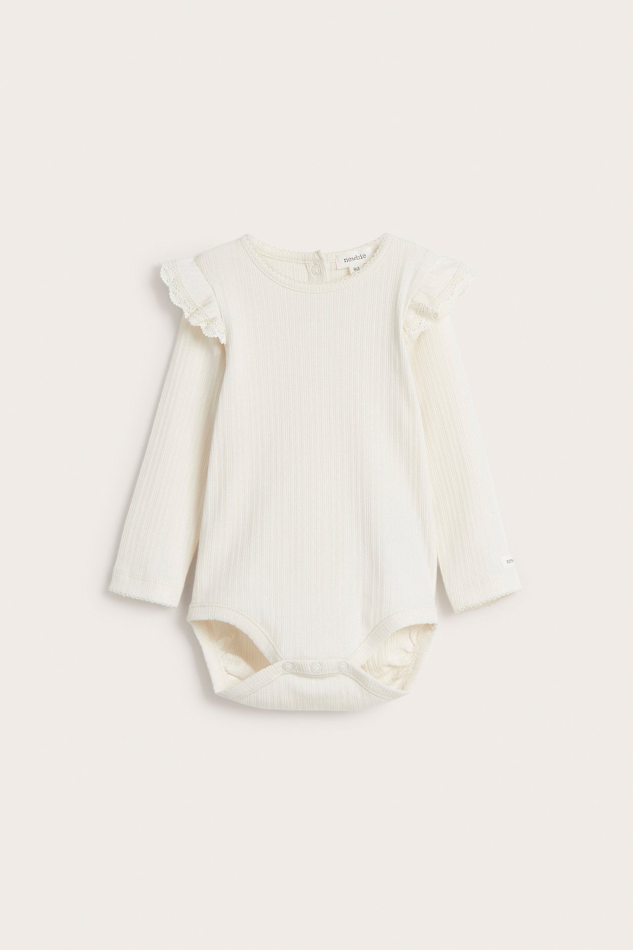 Frontvisning av en offwhite ribbet langermet babybody med blonderuffles på skuldre og trykknapper.