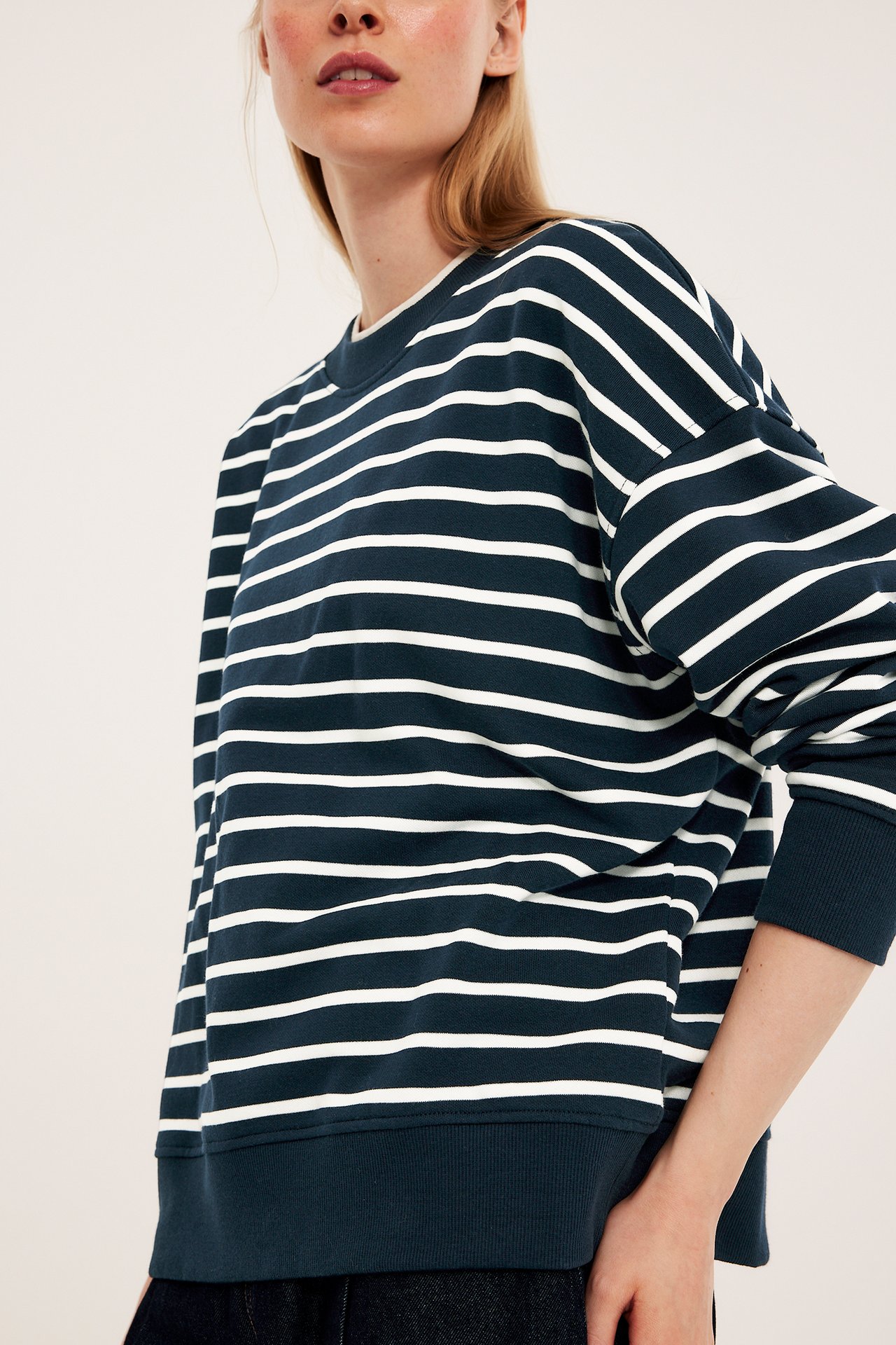 Frontvy: kvinna i en mörkblå och vitrandig sweatshirt i bomullsblandning med ribbade detaljer.