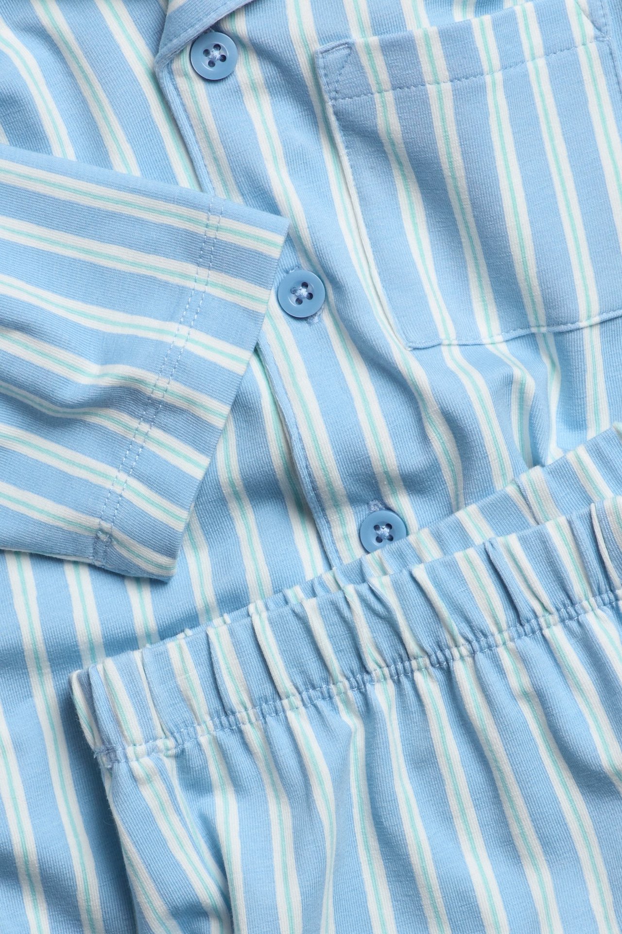 Zbliżenie na dziecięcą piżamę w jasnoniebieskie paski z dżerseju z guzikami i elastyczną talią.