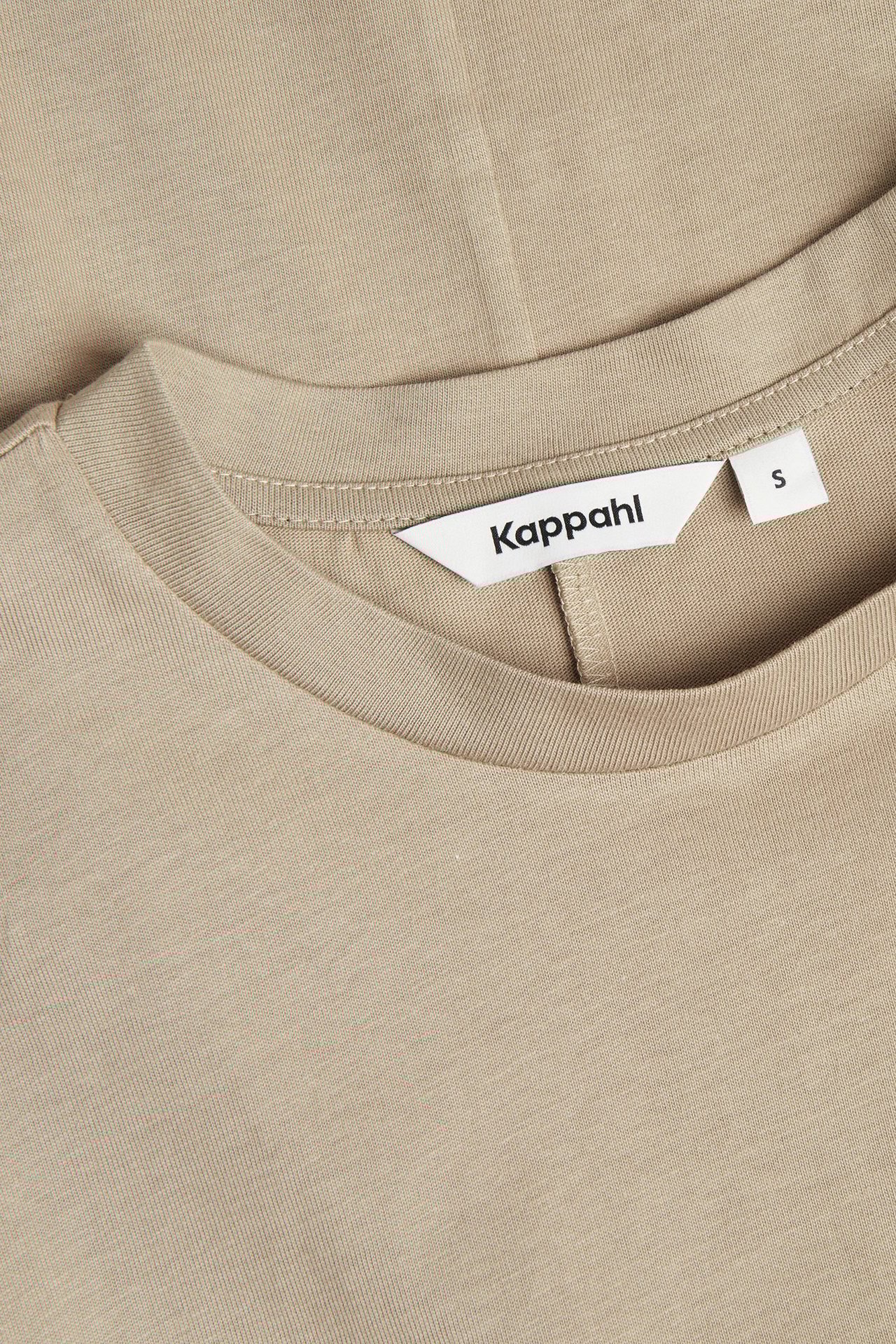 Zbliżenie beżowej krótkiej sukienki z bawełnianego dżerseju z okrągłym dekoltem.