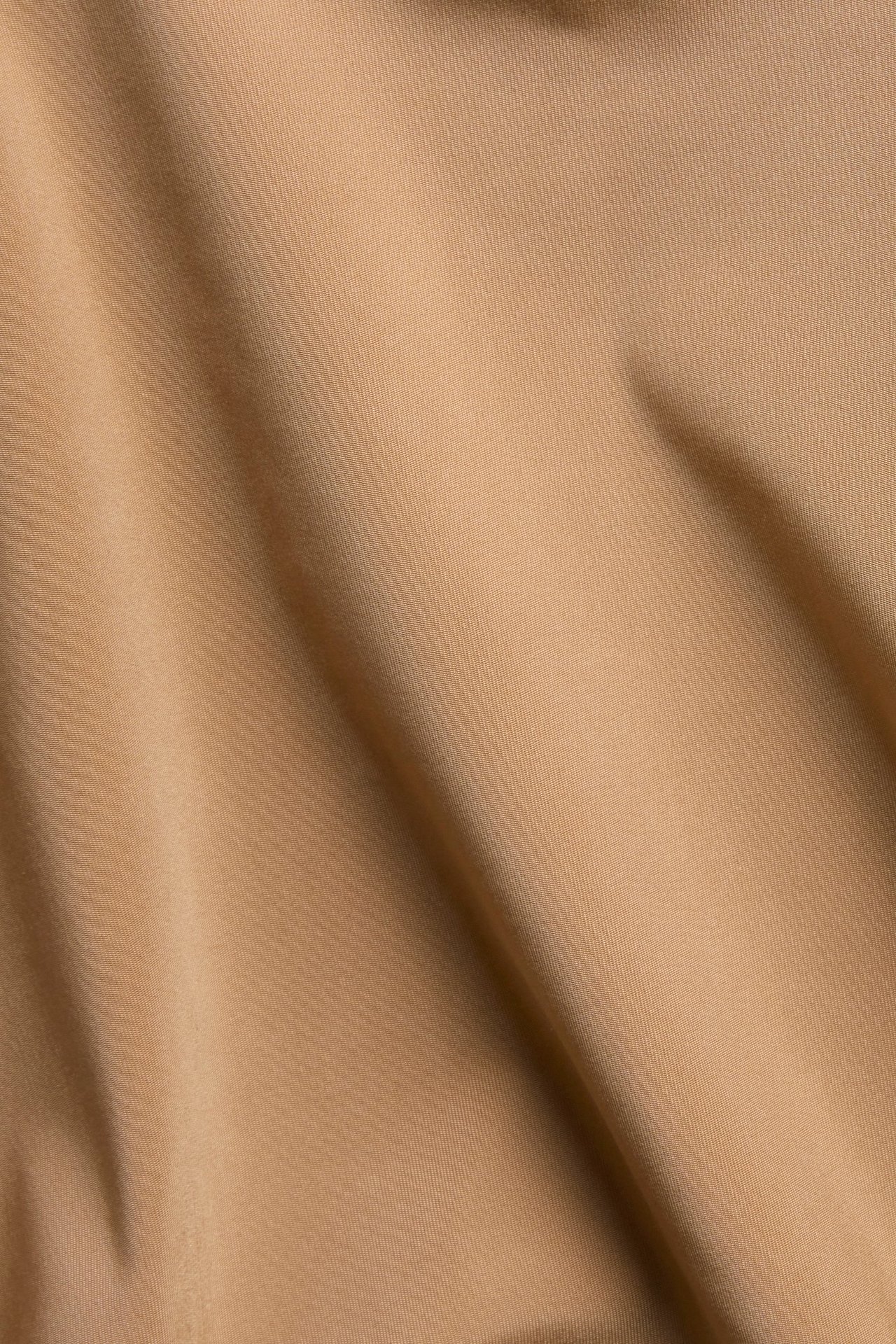 Zbliżenie na jednolity brązowy materiał mikrofibrowych fig typu hipster z miękkimi fałdami.