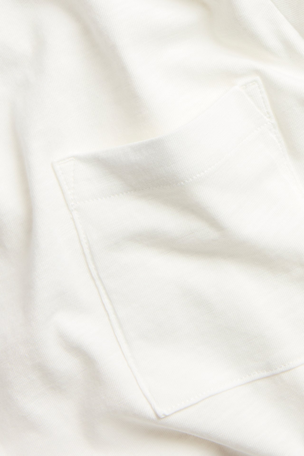 Zbliżenie na kremowy, długi rękaw z bawełny slub z naszywaną kieszenią.