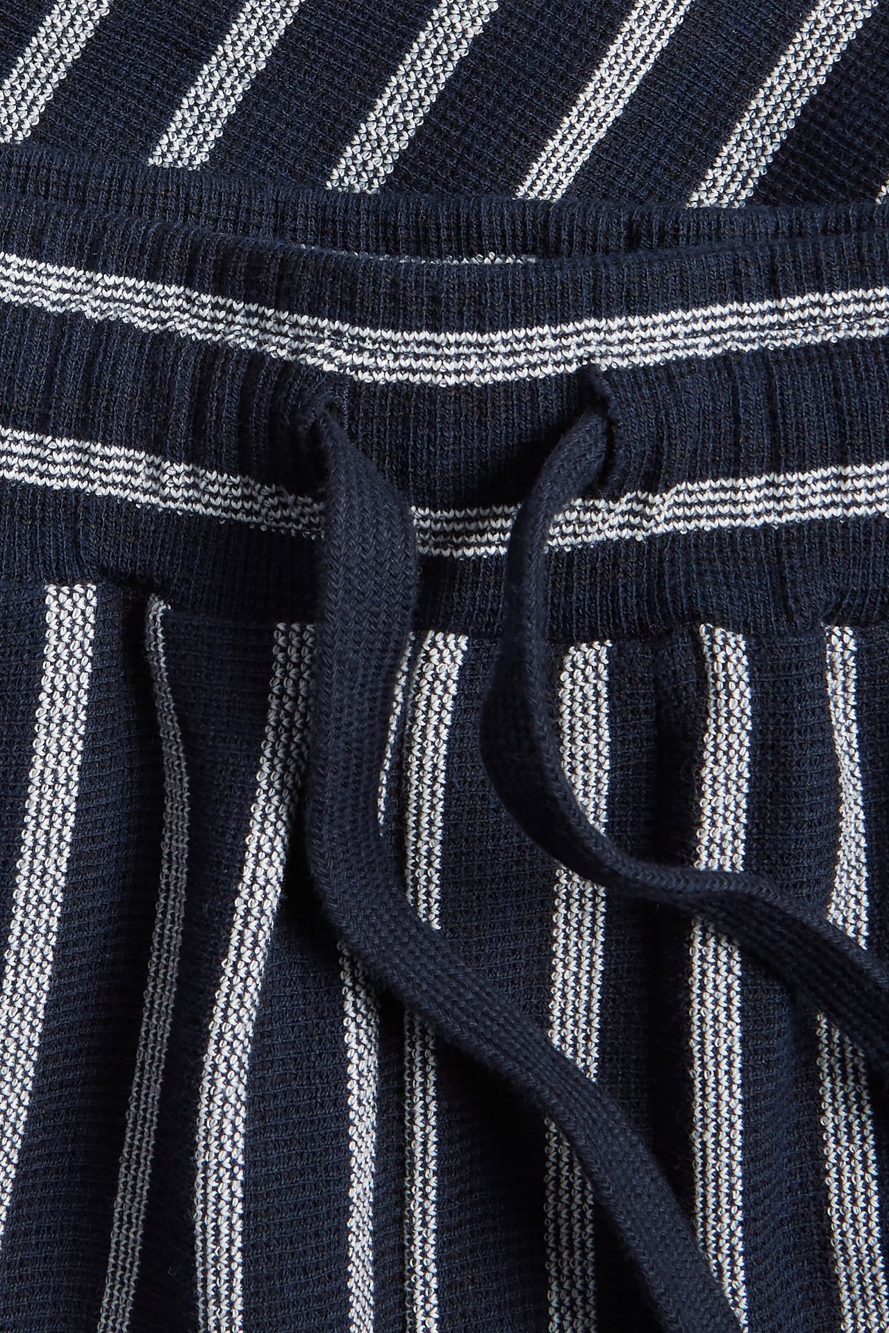 Zbliżenie na granatowe szorty w paski z teksturowanej tkaniny z granatowym sznurkiem.