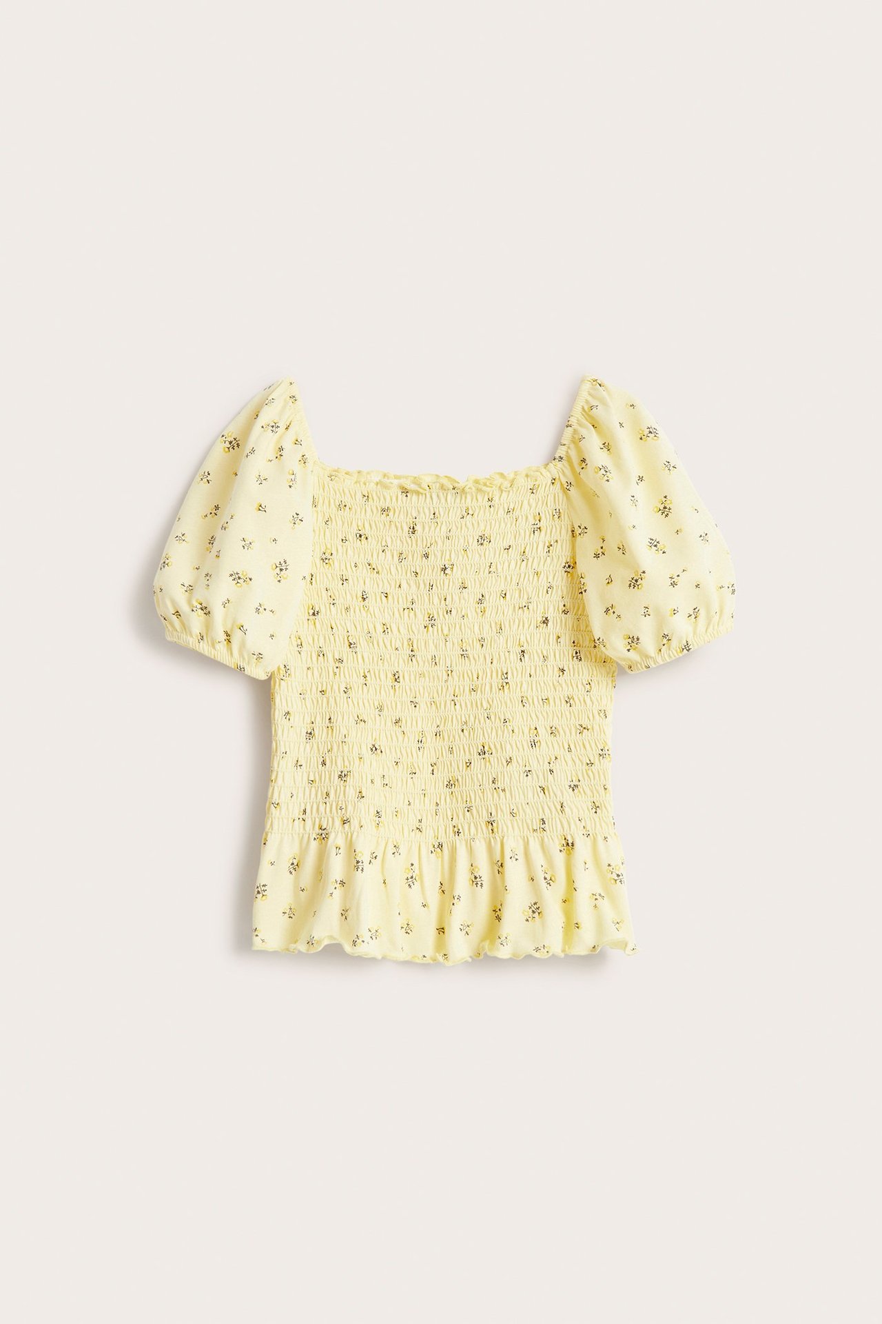 Framifrån, ljusbeige blommig smockad bomullstopp med puffärmar och fyrkantig halsringning.