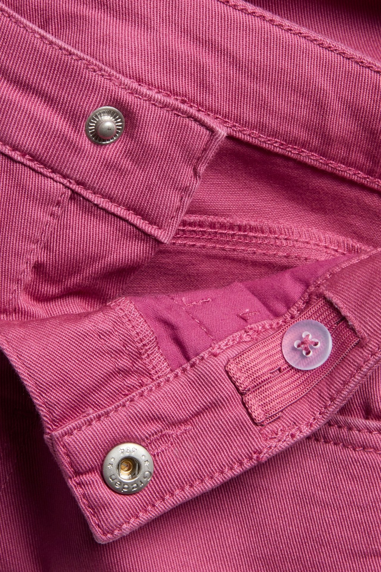 Zbliżenie na ciemnoróżowe jeansy bootcut z twillu ze srebrnym zatrzaskiem i regulowaną wewnętrzną gumką.