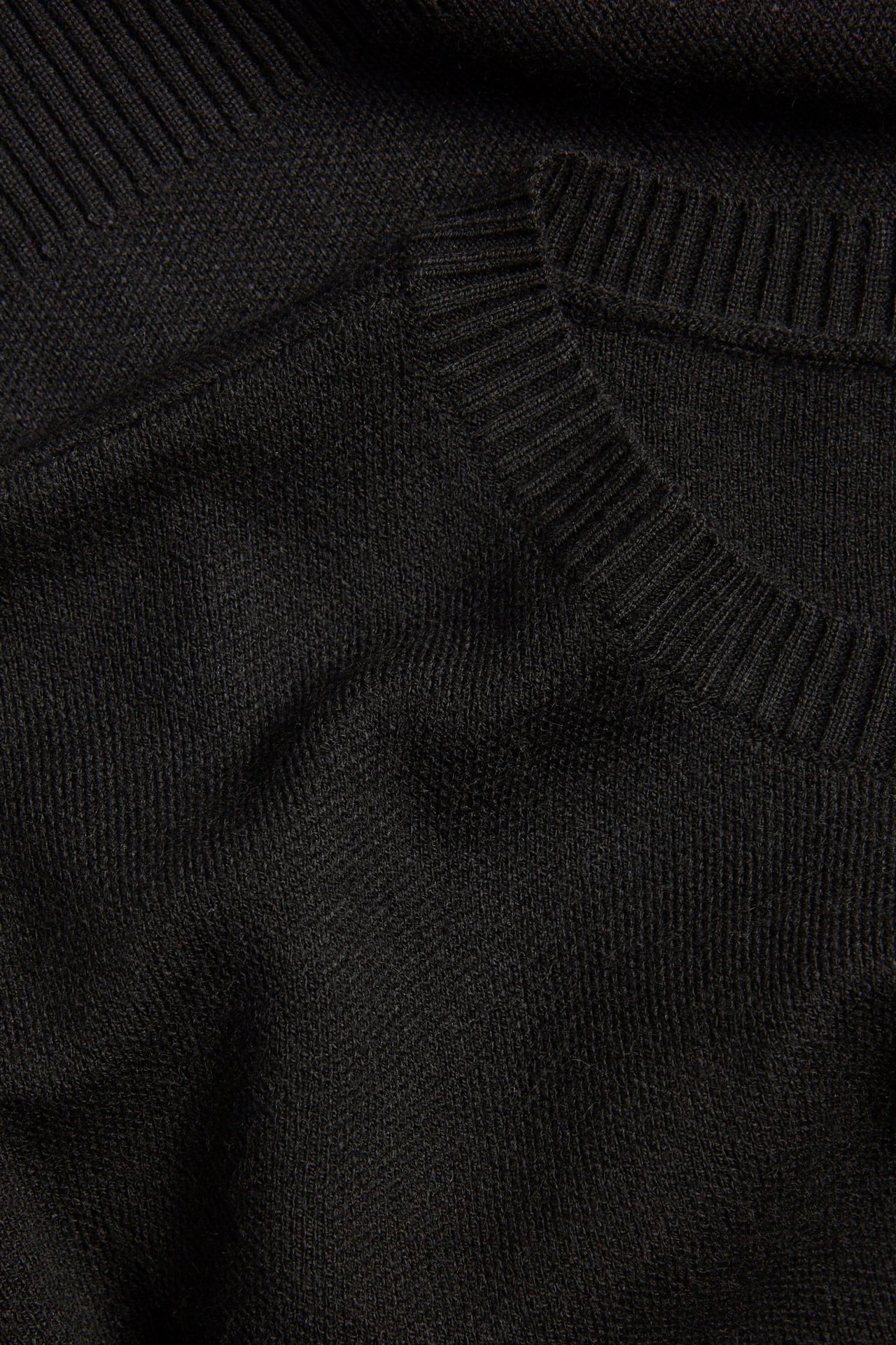 Zbliżenie czarnego, dzianinowego swetra z okrągłym dekoltem i prążkowanym kołnierzem.