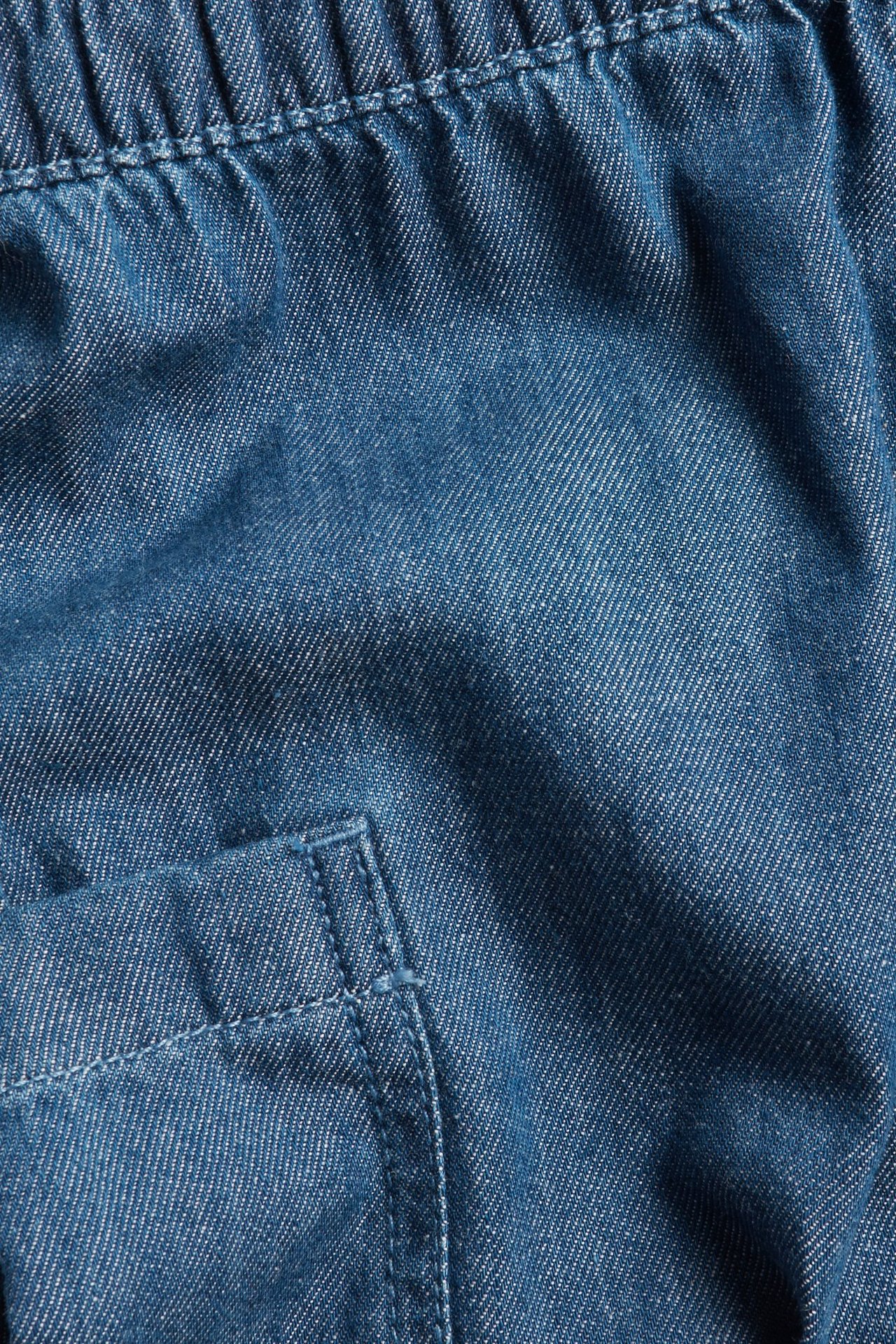 Zbliżenie niebieskich dżinsowych spodni niemowlęcych z elastyczną talią i boczną kieszenią.