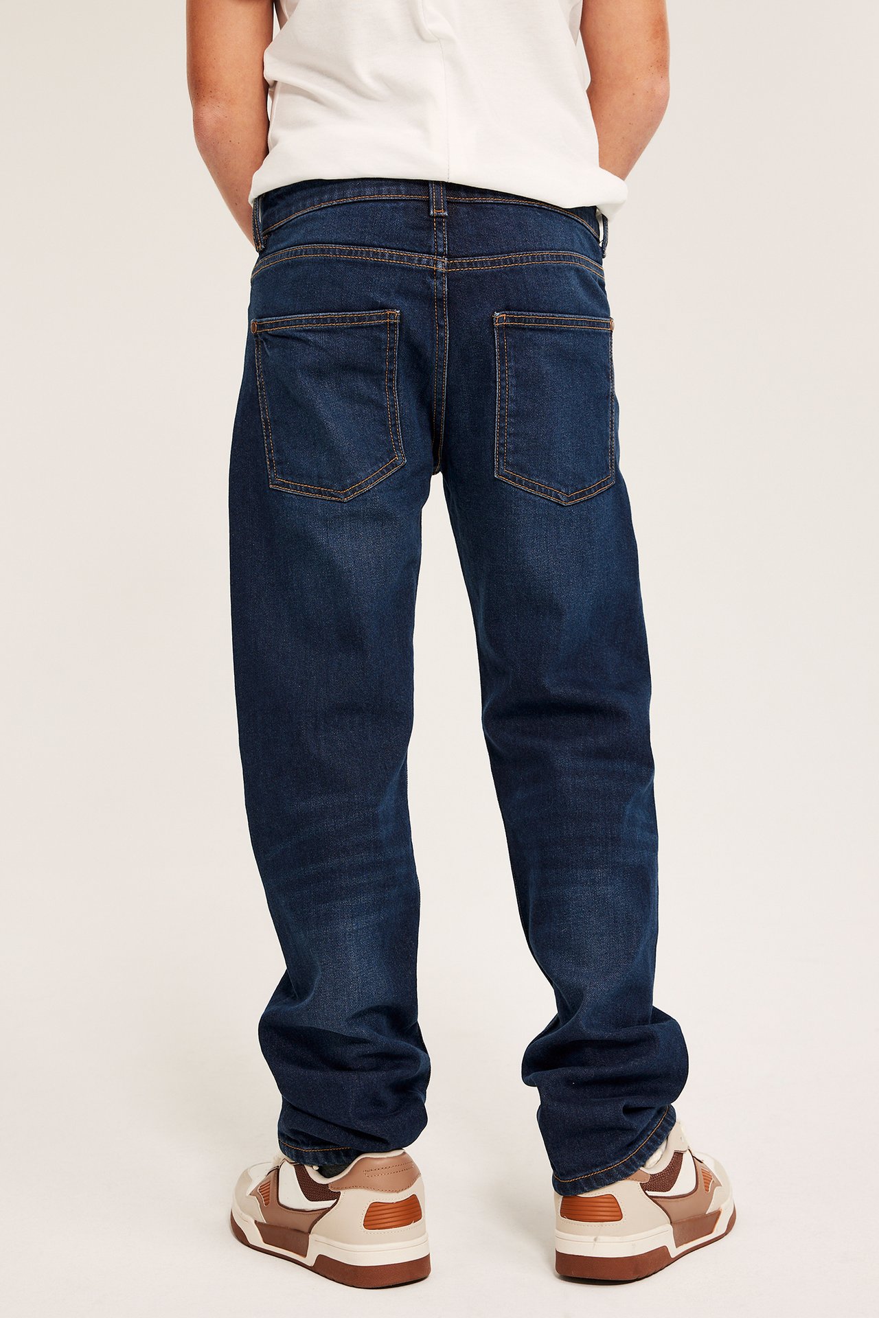 Person i mörkblå jeans med rett passform, midje, stretch, fem lomme, bak.