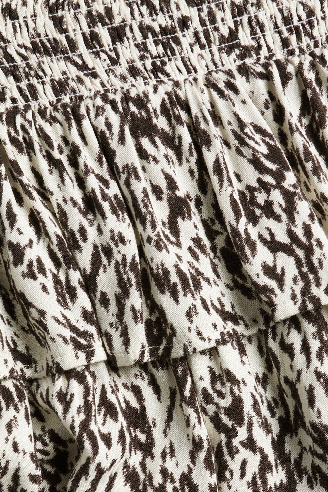 Zbliżenie beżowej wzorzystej spódnicy z wiskozy z falbanami i marszczoną talią.